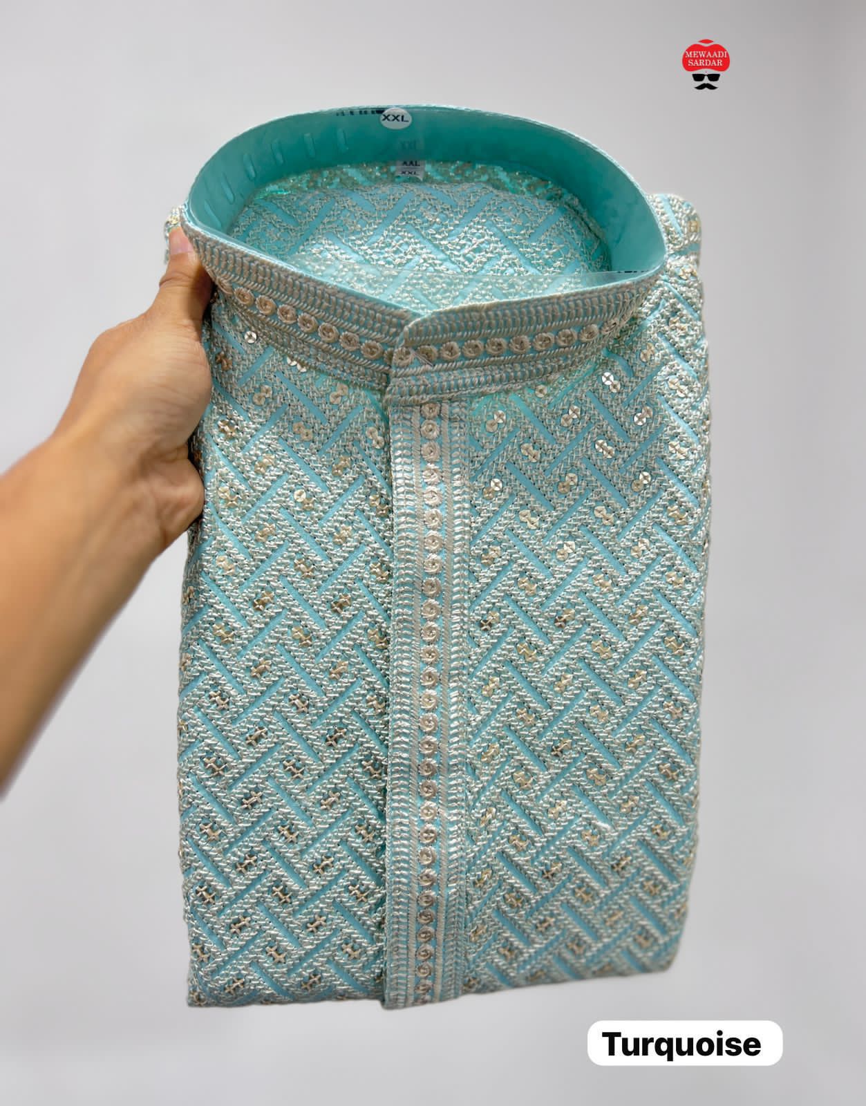 Turquoise embroidered fabric held by a hand on a background