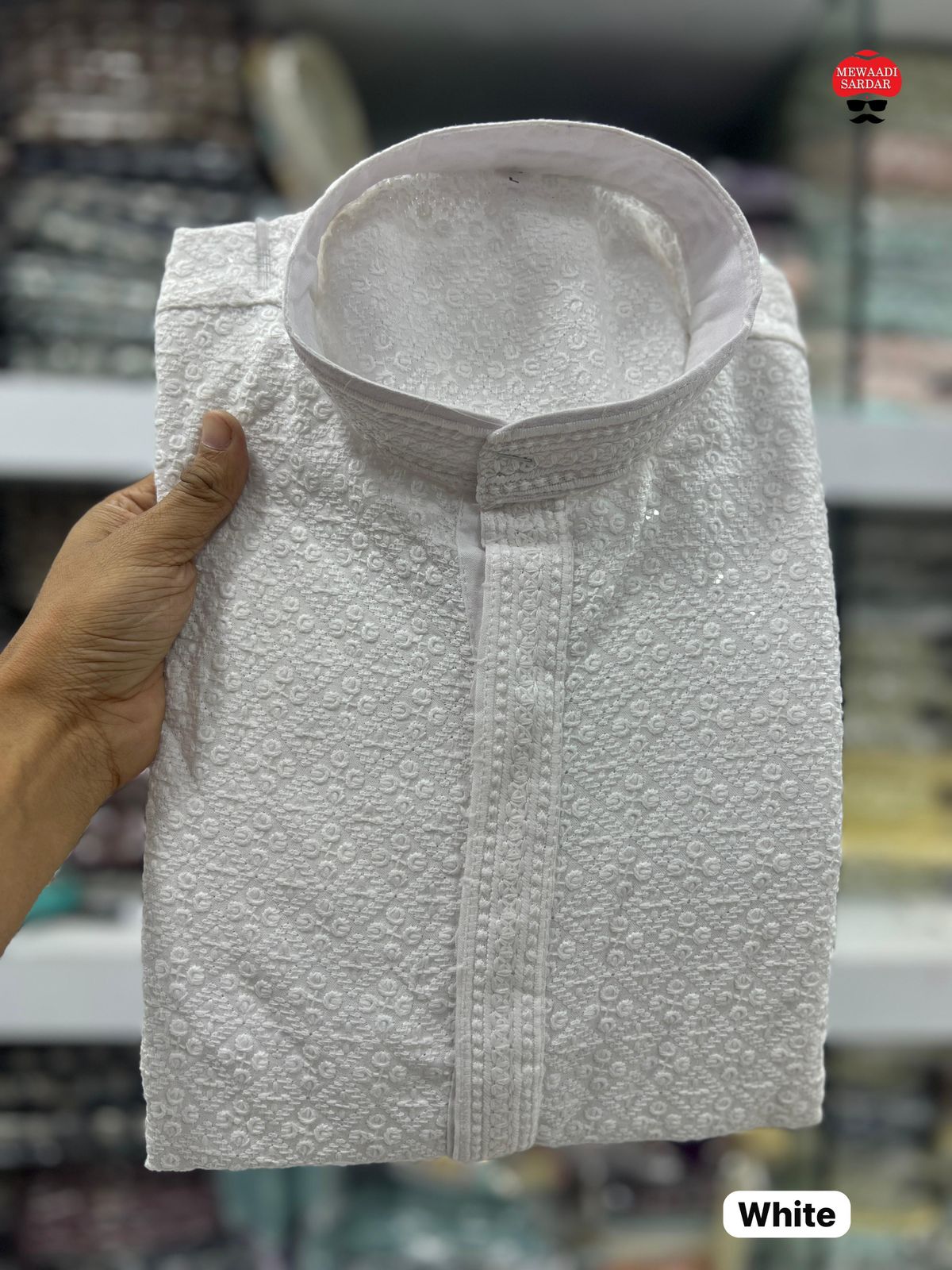 White textured shirt held by a hand with a blurred background