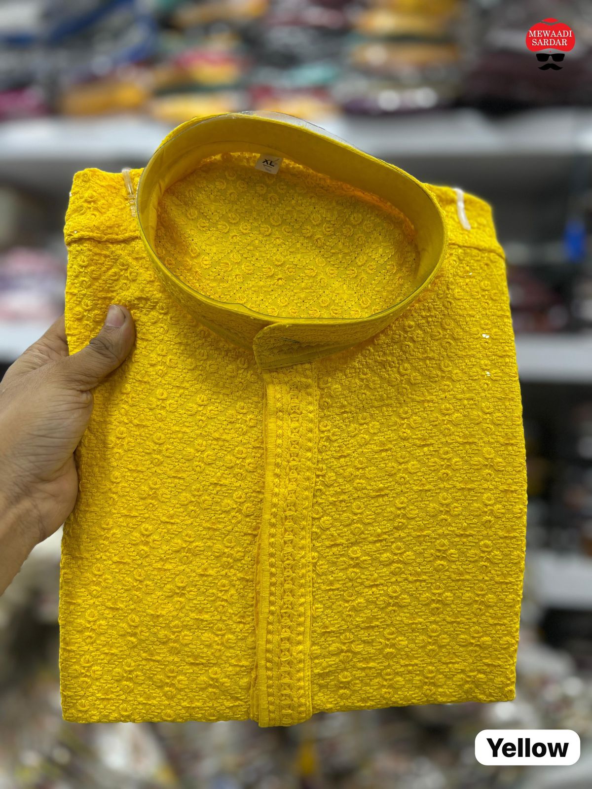 Yellow jacket held by a hand with a blurred store background