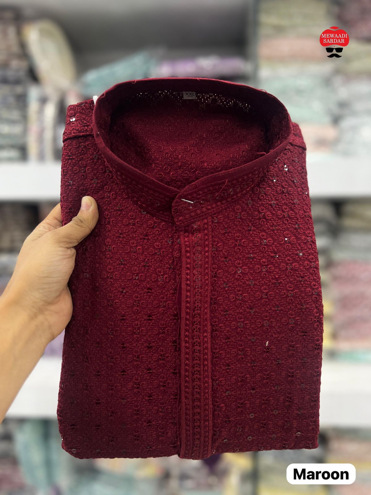 Maroon shirt held by a hand with a blurred store background