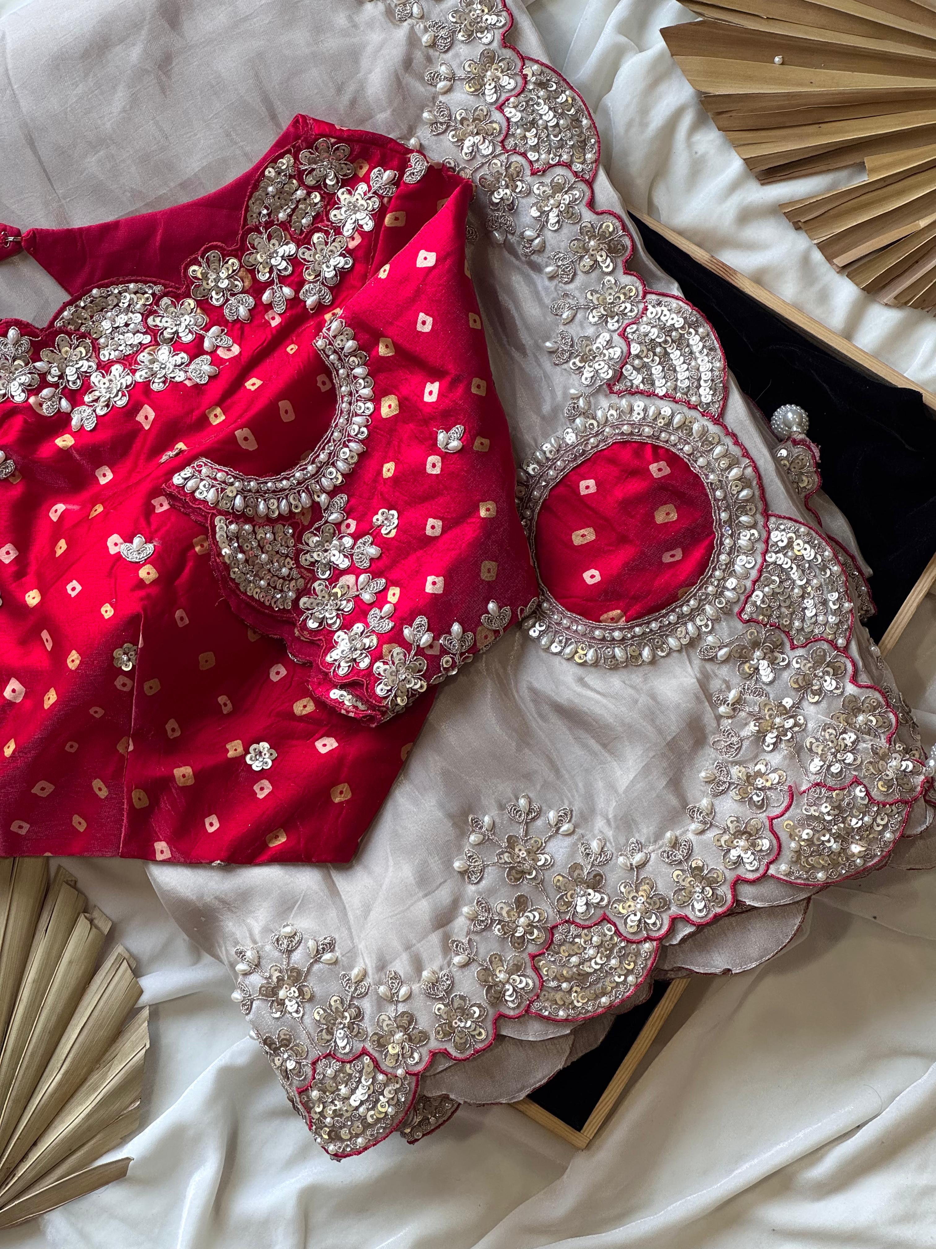 Red blouse with silver embroidery on a white fabric background