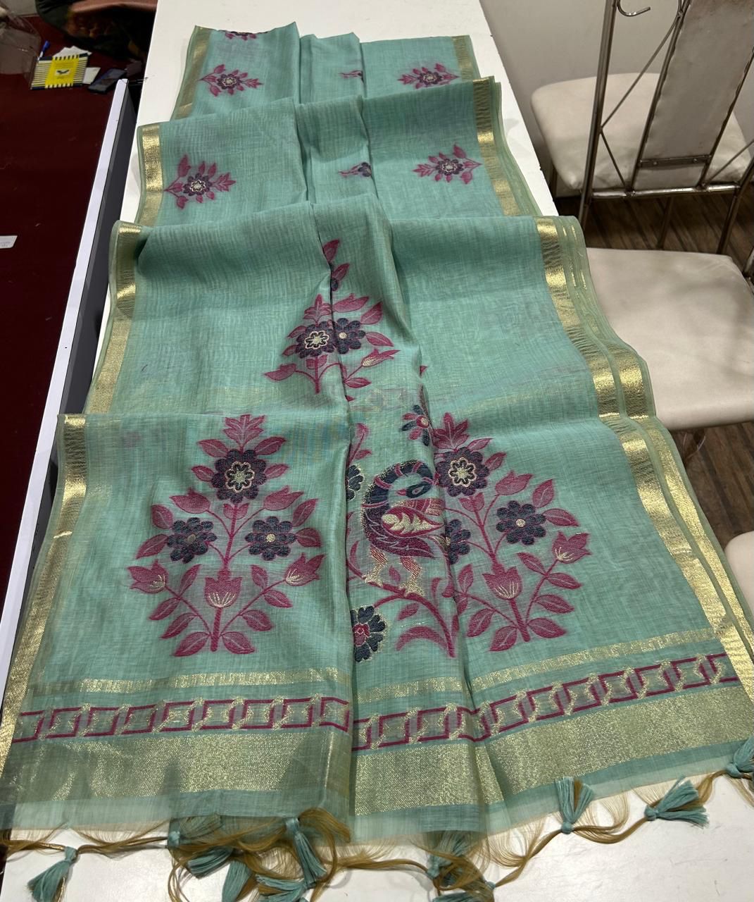 Teal blue saree with floral patterns on a white table