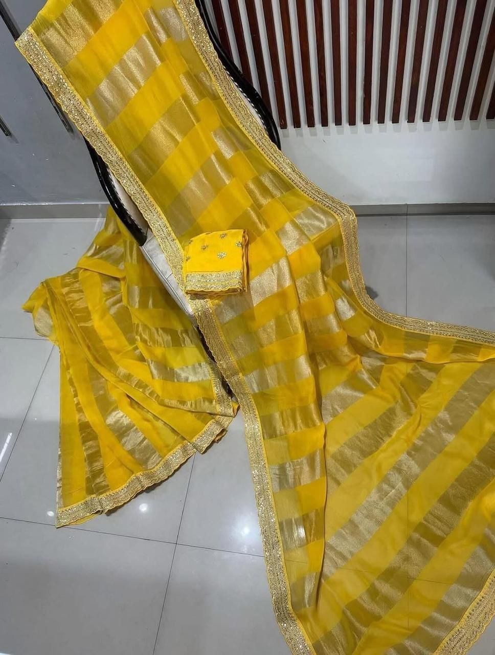 Yellow saree with gold border on a tiled floor