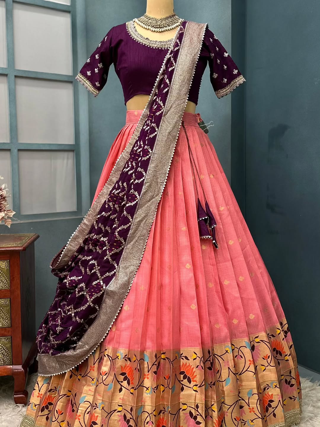 Peach lehanga Traditional Indian outfit on a mannequin against a blue wall.