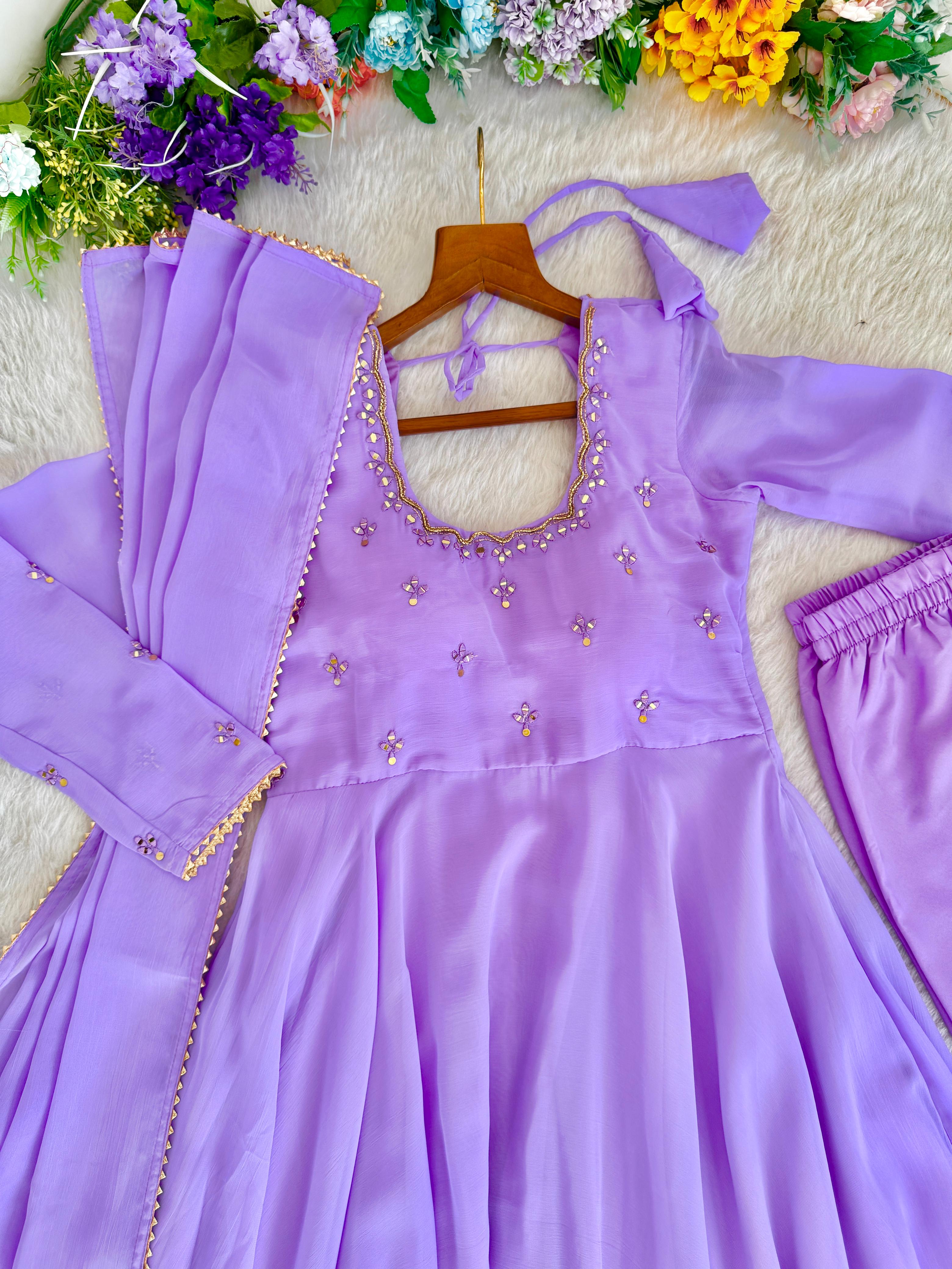 Purple dress with floral embellishments on asurface with flowers in the background