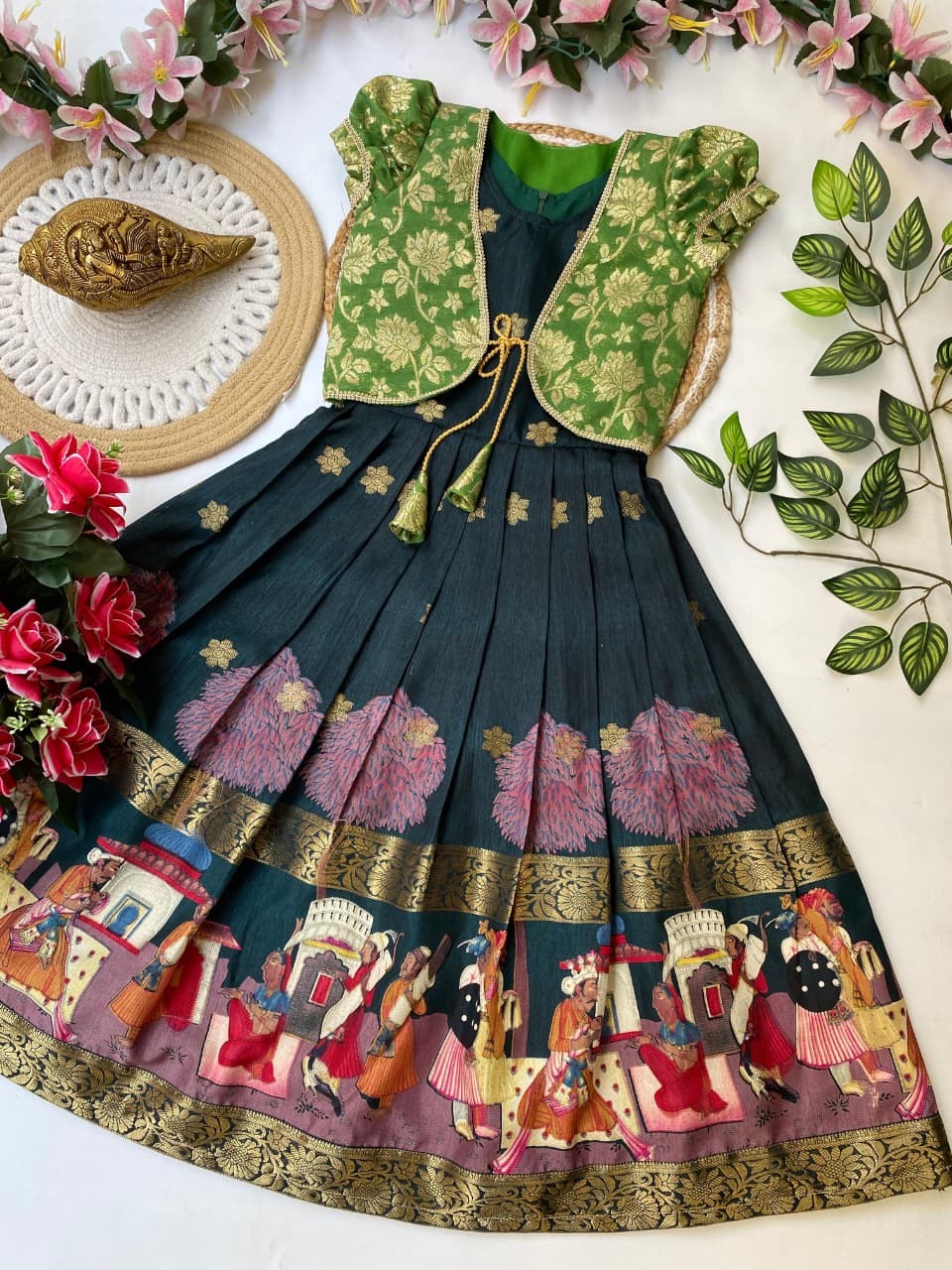 Traditional outfit with blouse and dark green skirt featuring colorful patterns on a white background with flowers and leaves.