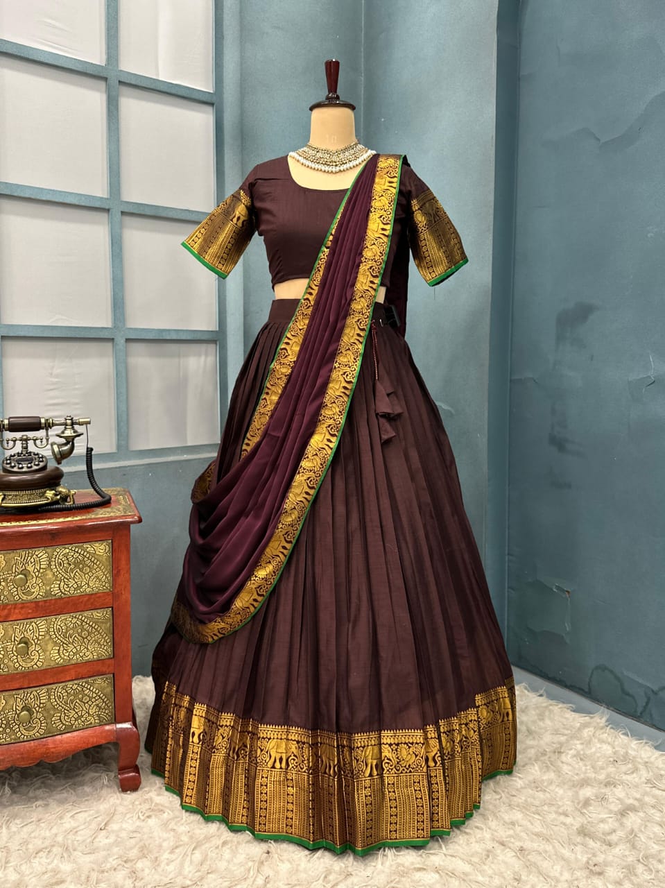 Brown and gold traditional outfit on a mannequin against a blue wall.
