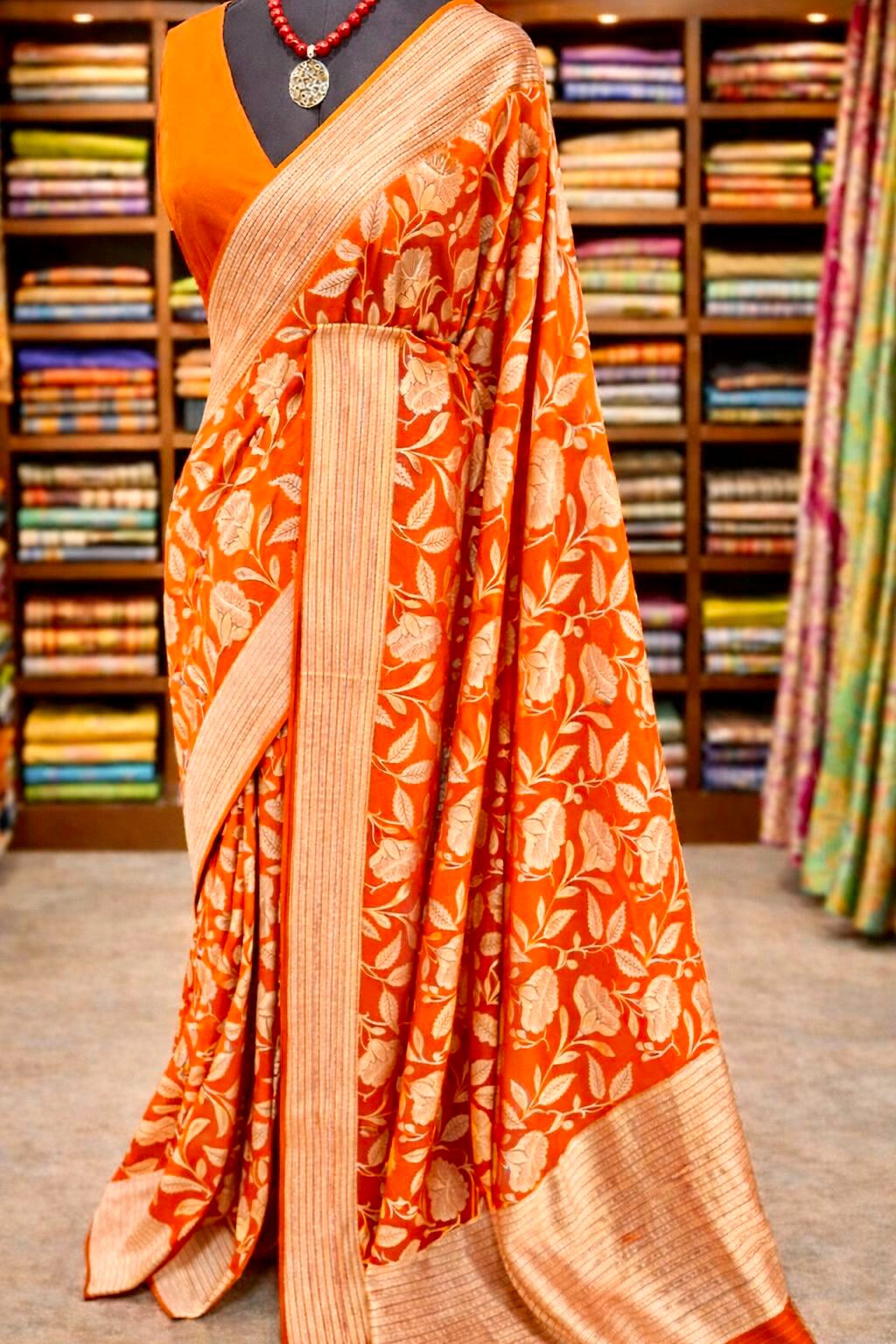Orange saree with floral patterns in a store setting