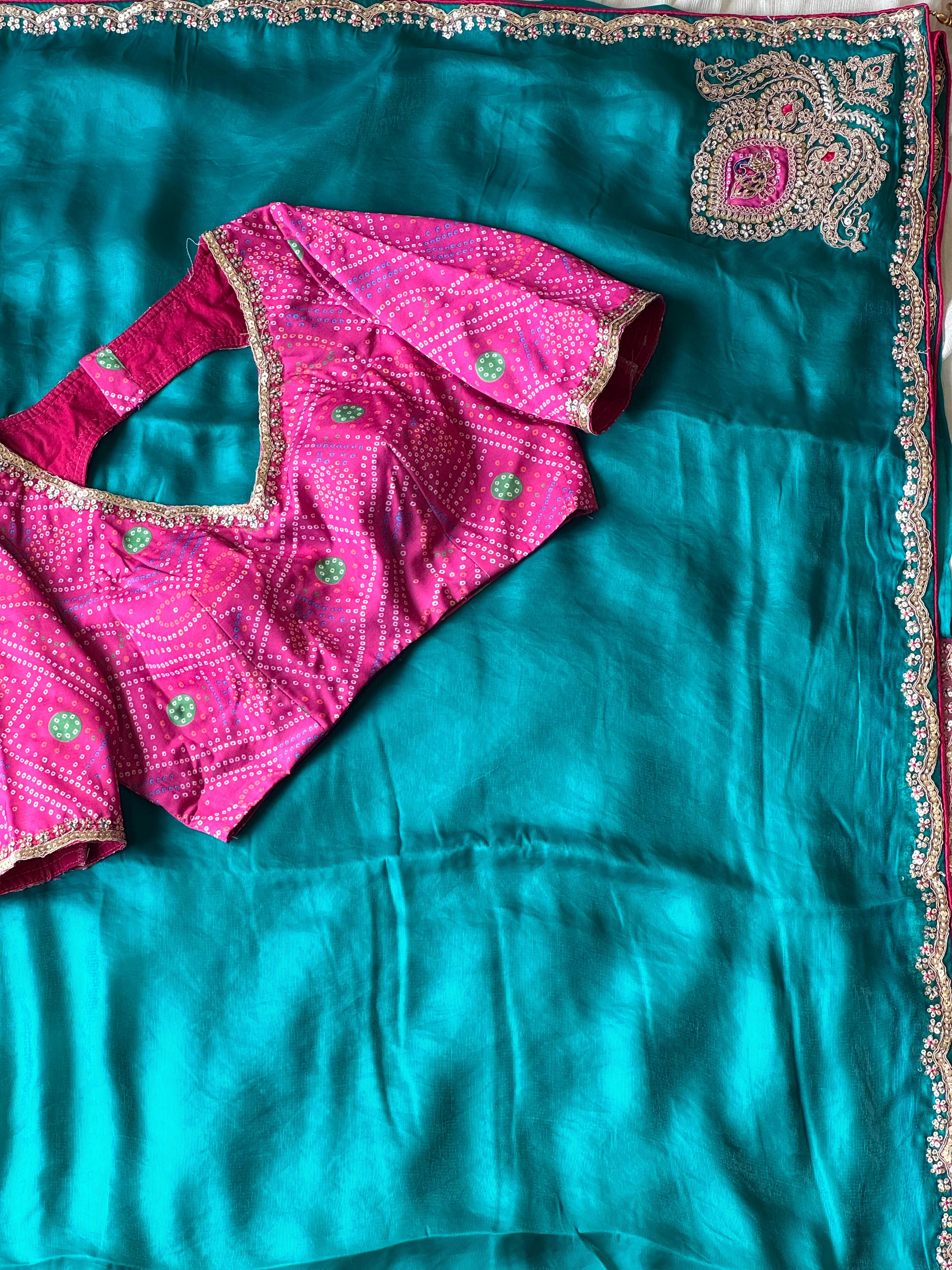 Teal blue saree with pink blouse on a matching fabric background