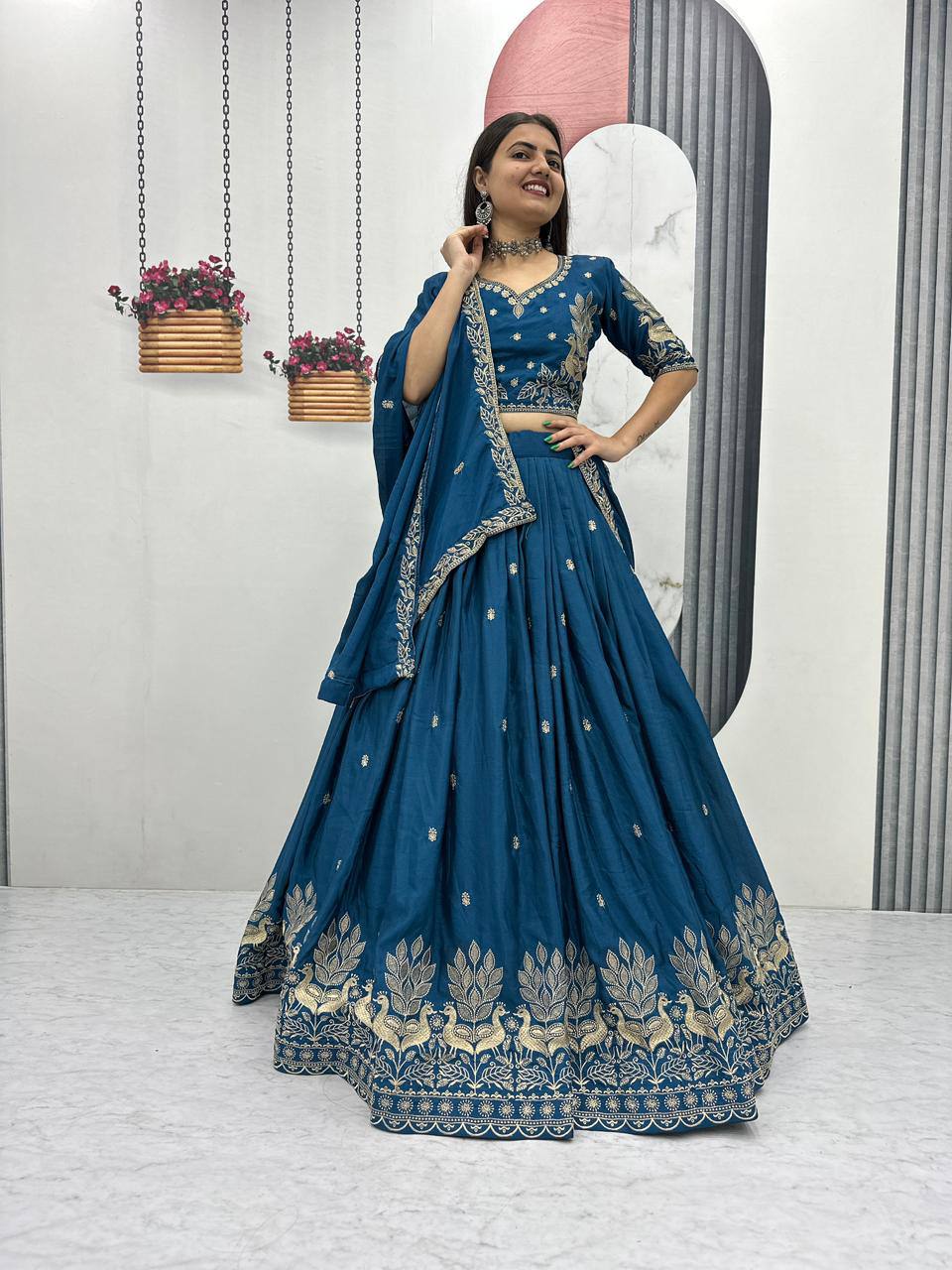 Woman in a blue embroidered traditional outfit standing in front of a mirror.