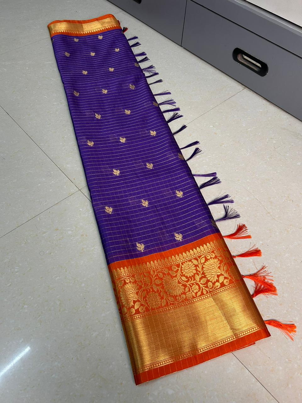 Purple and orange saree with gold border on a white floor