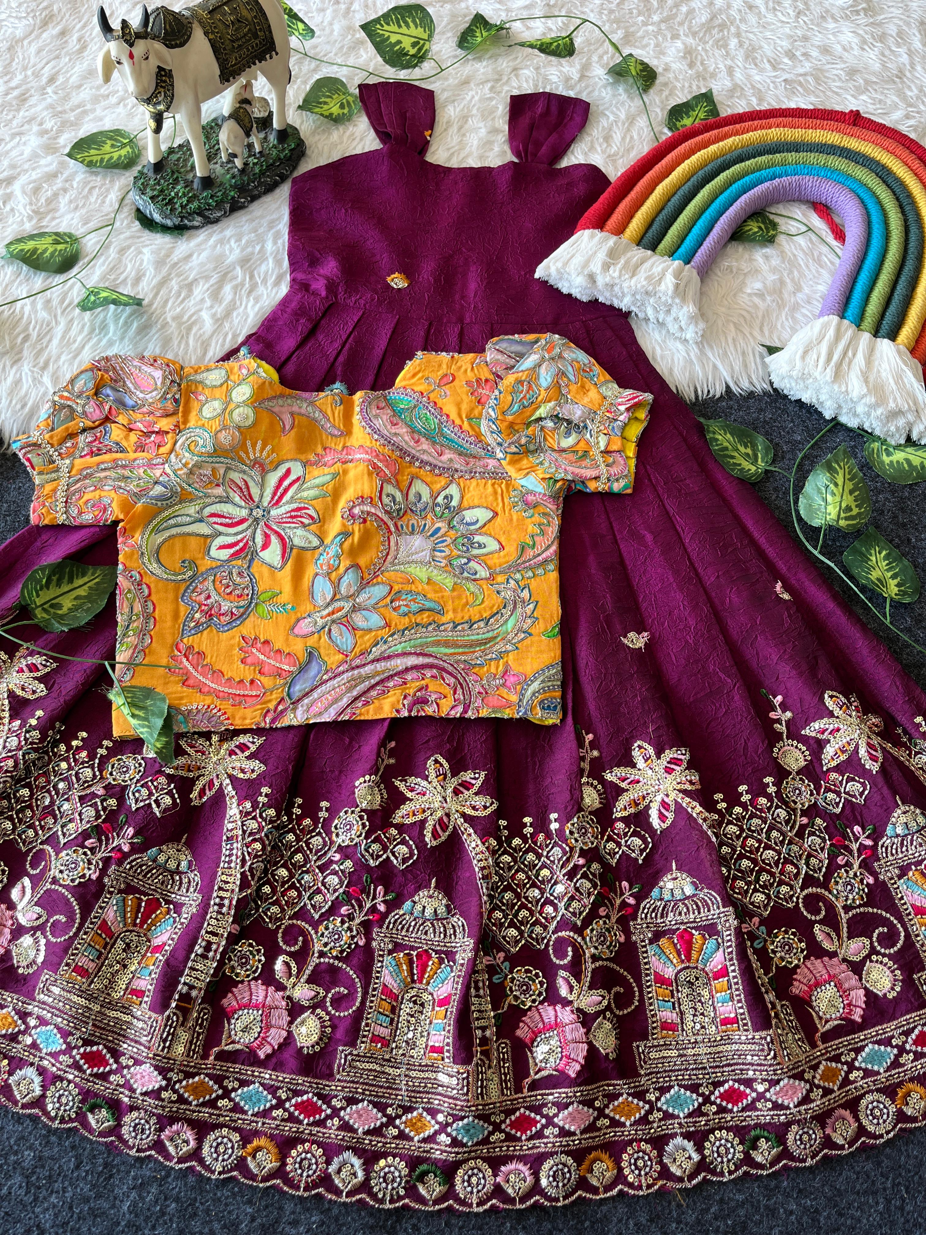 Rani pink embroidered traditional outfit with a colorful top and decorative elements on a textured surface.