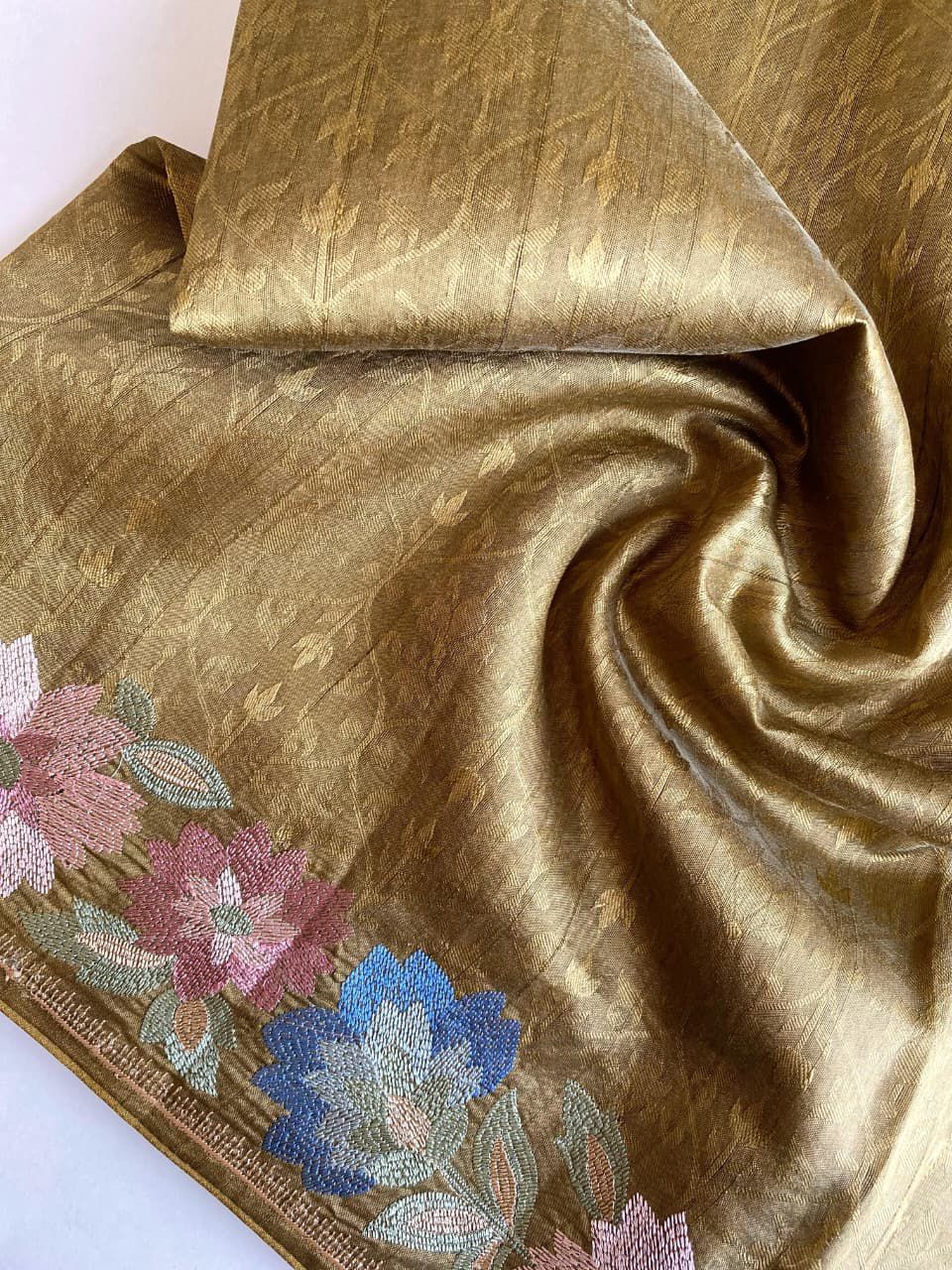 Gold fabric with floral embroidery on a white background