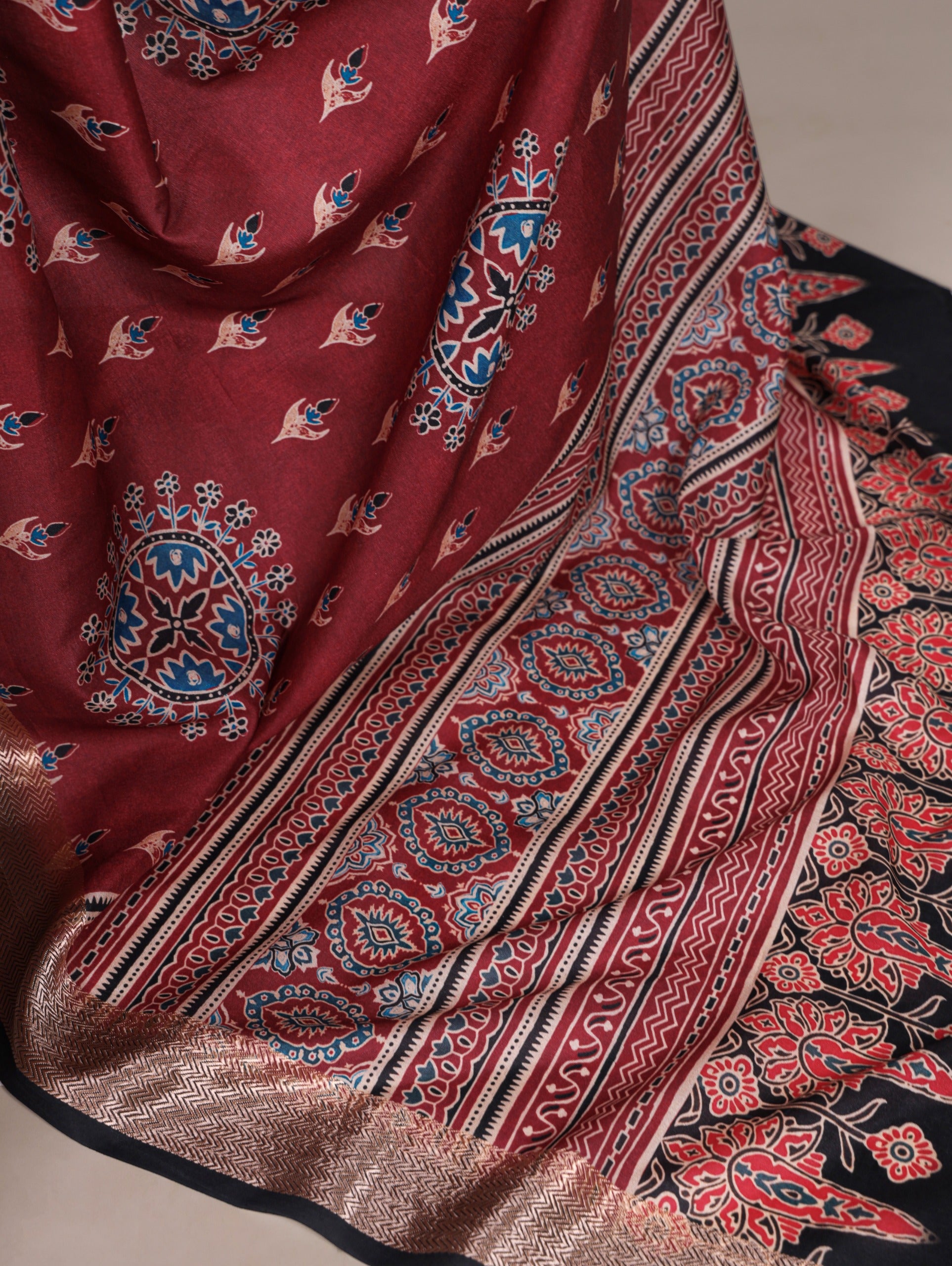 Maroon patterned fabric with intricate designs on a neutral background