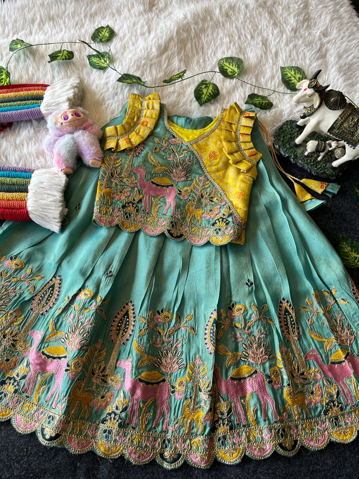 Cyan Embroiderey traditional outfit with colorful patterns on a textured surface.