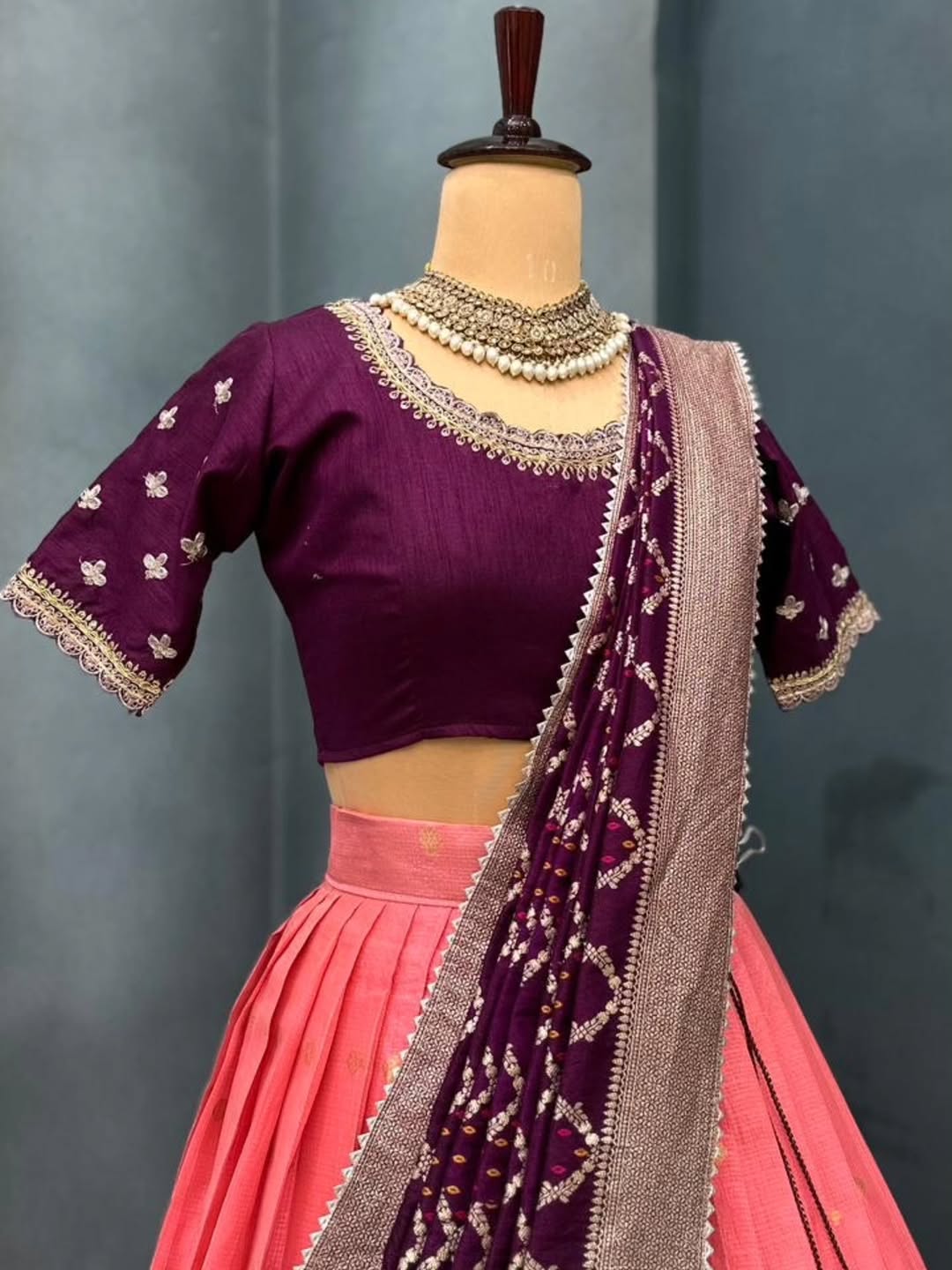 Peach lehanga with matching dupatta on a mannequin against a gray background