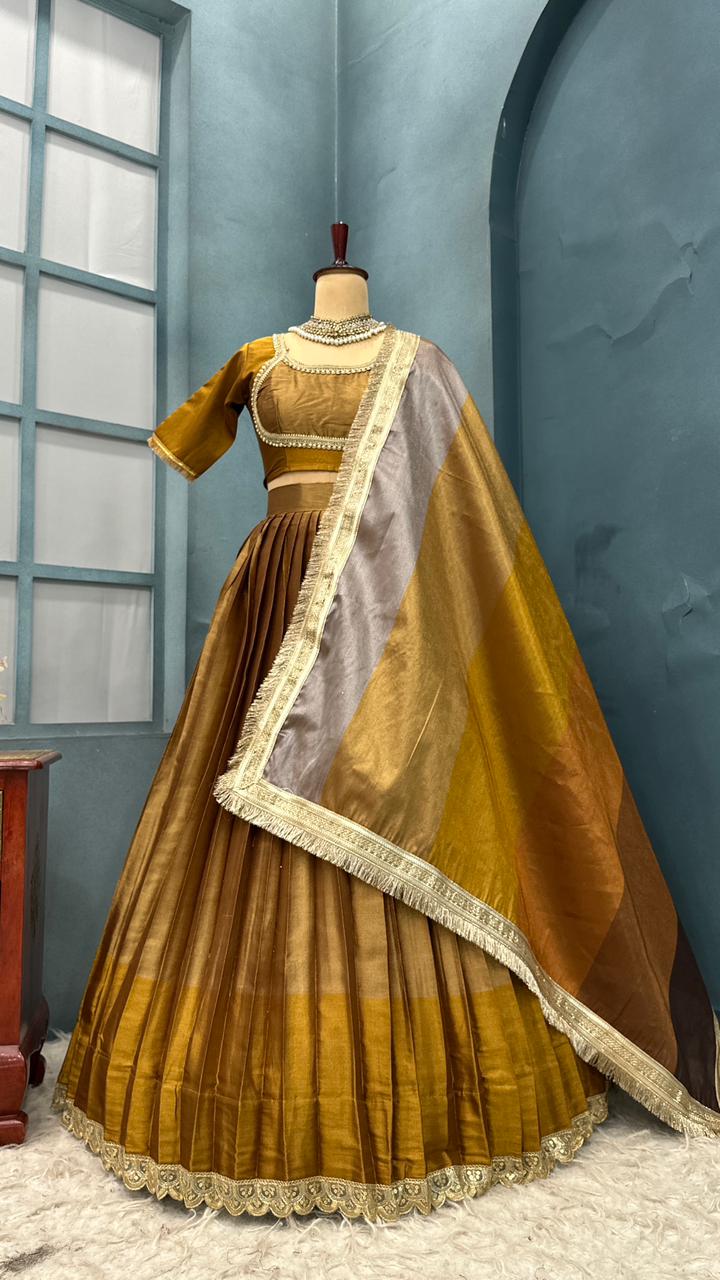 Traditional outfit with a brown and gold dress and dupatta on a mannequin against a blue wall.