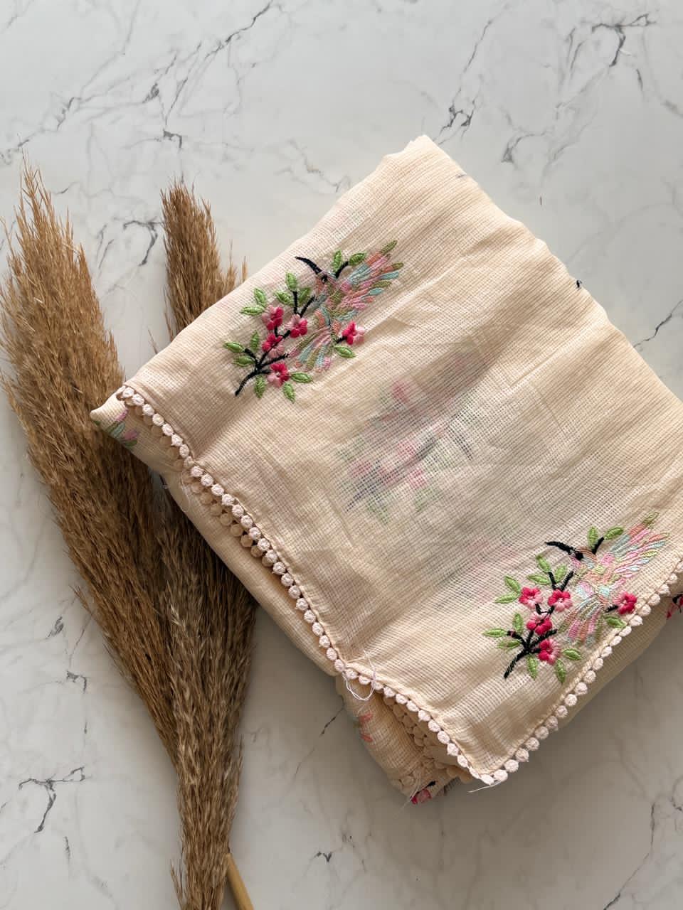 Beige fabric with floral embroidery on a marble surface
