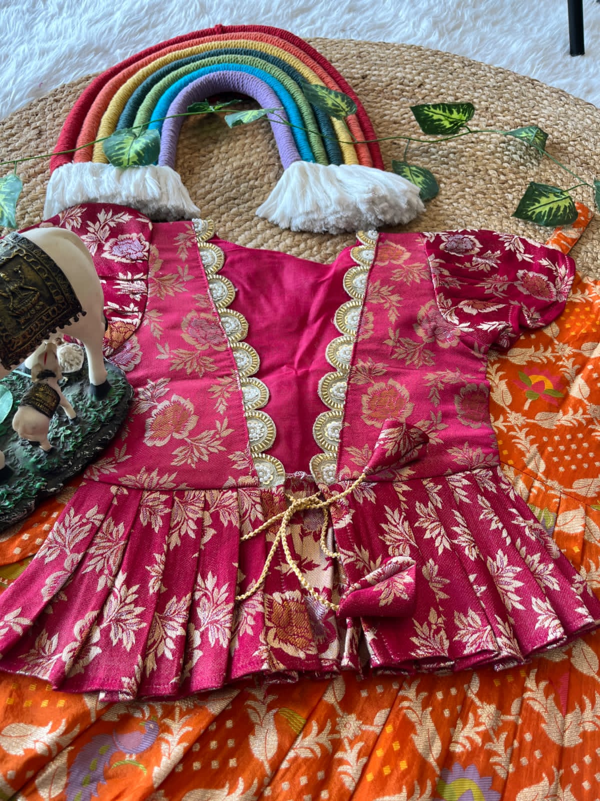 Colorful Orange traditional outfit and rainbow-shaped bag on a surface.