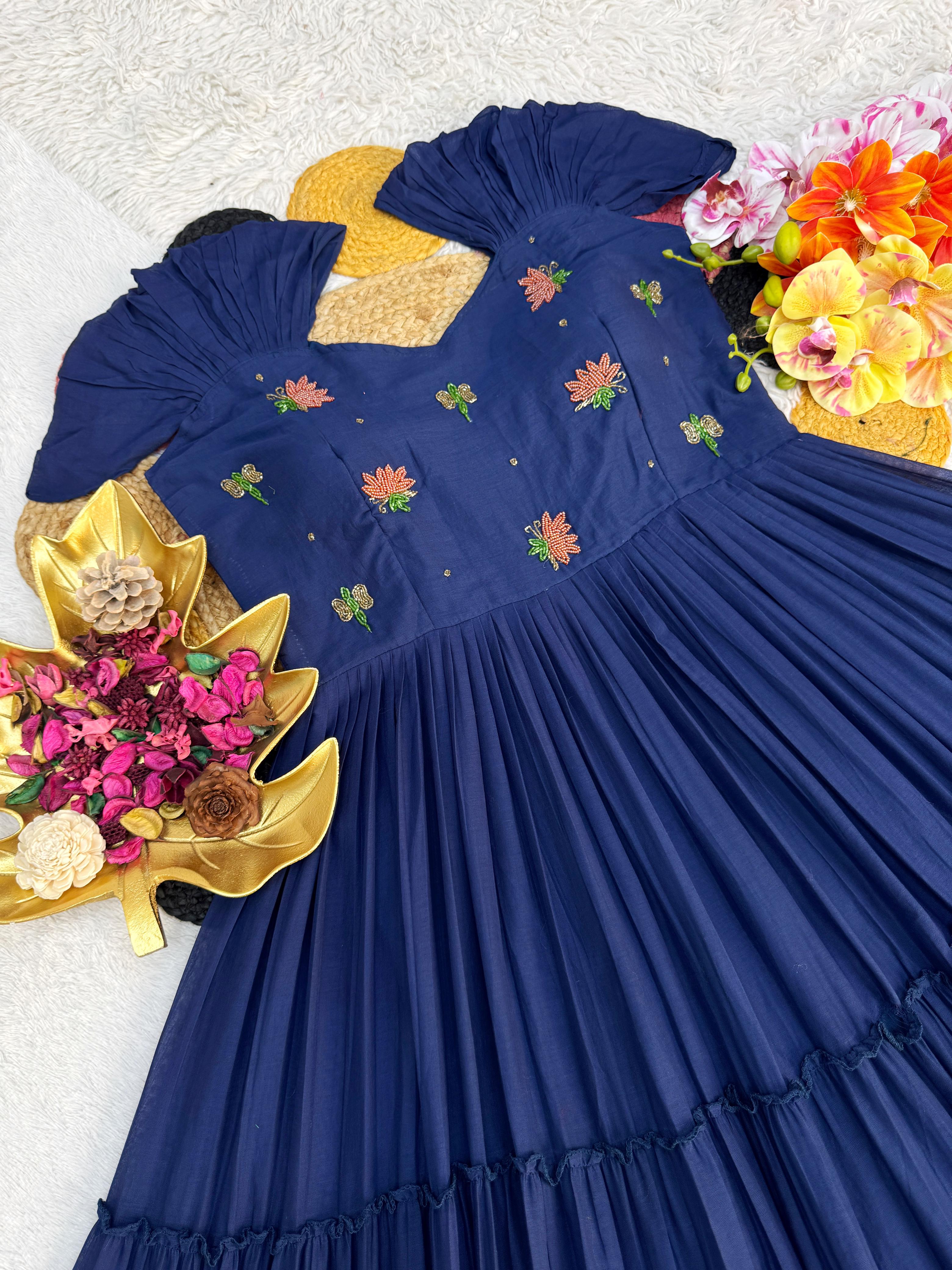 Navy blue dress with floral embroidery on a textured surface with flowers and leaves.