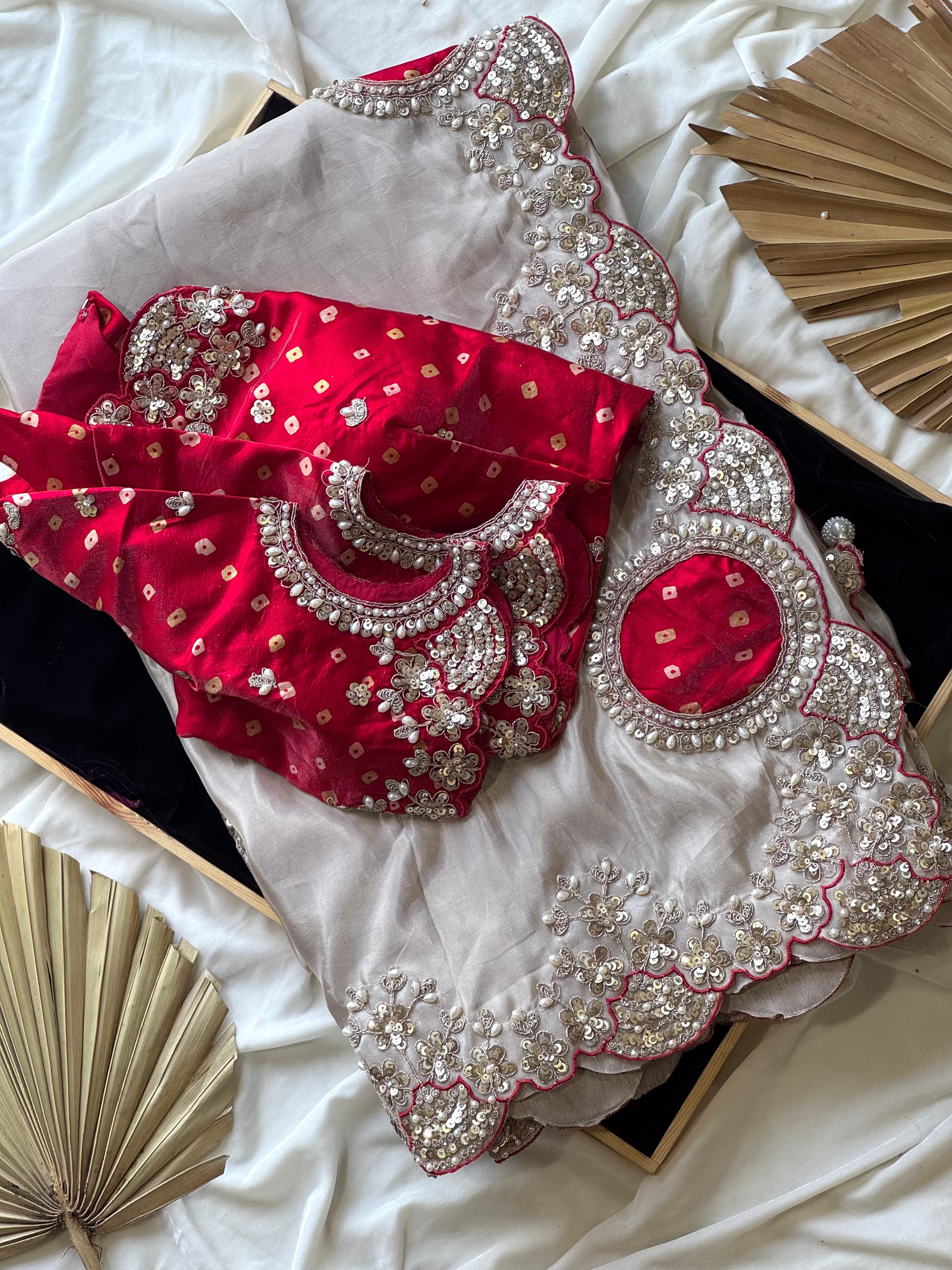 Red and silver embroidered blouse on a white fabric background with fans.