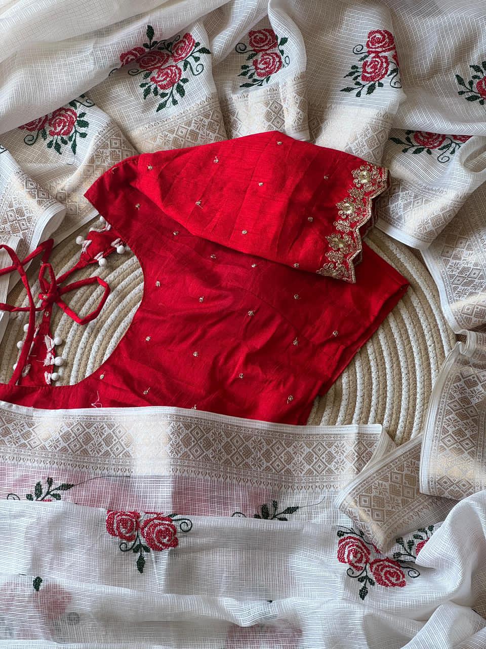 Red blouse with floral embroidery on a white fabric background
