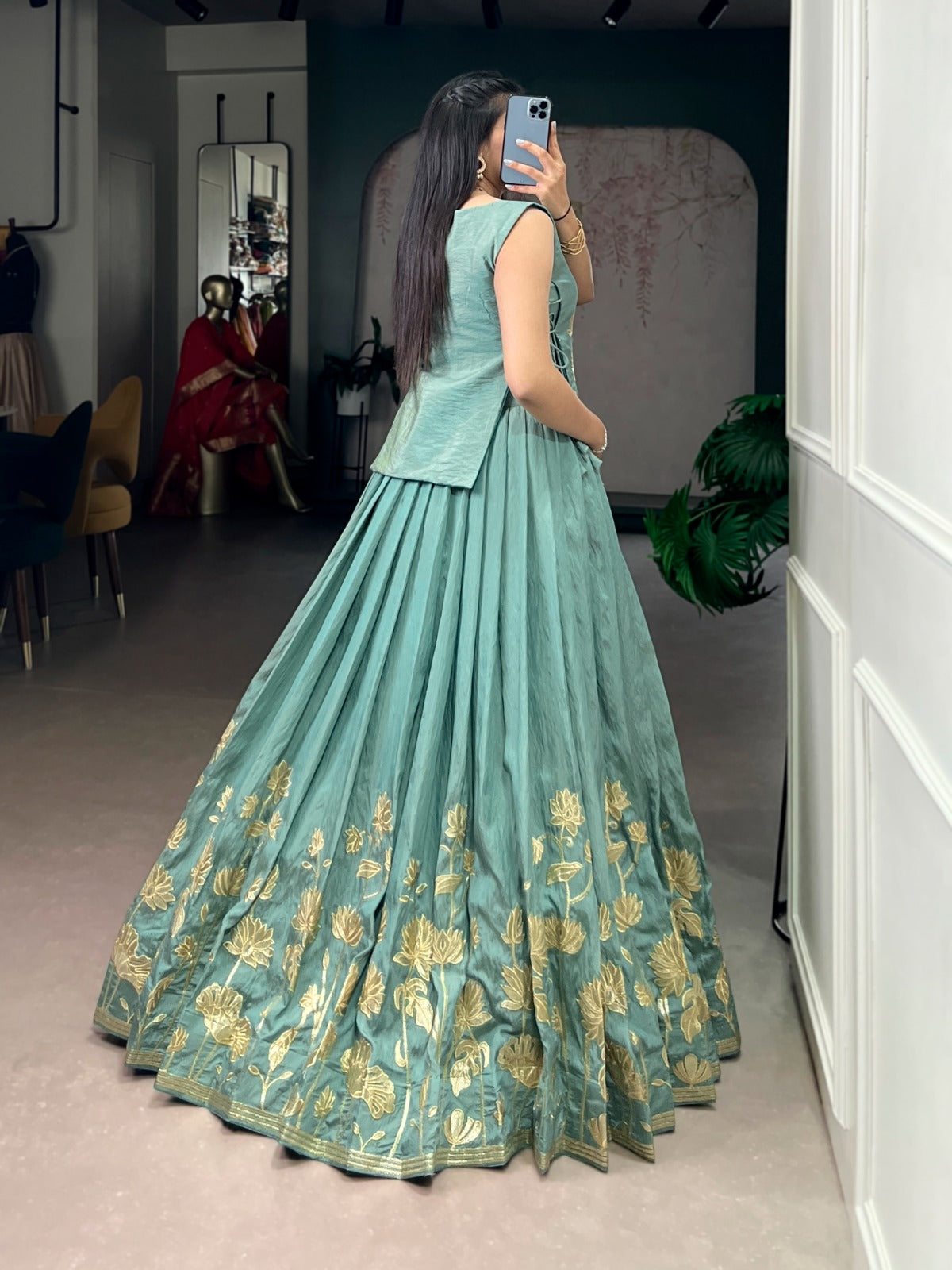 Sea green traditional outfit with gold patterns taking a mirror selfie.