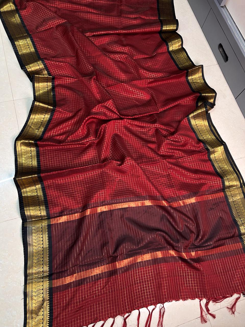 Red saree with gold and black border on a white floor