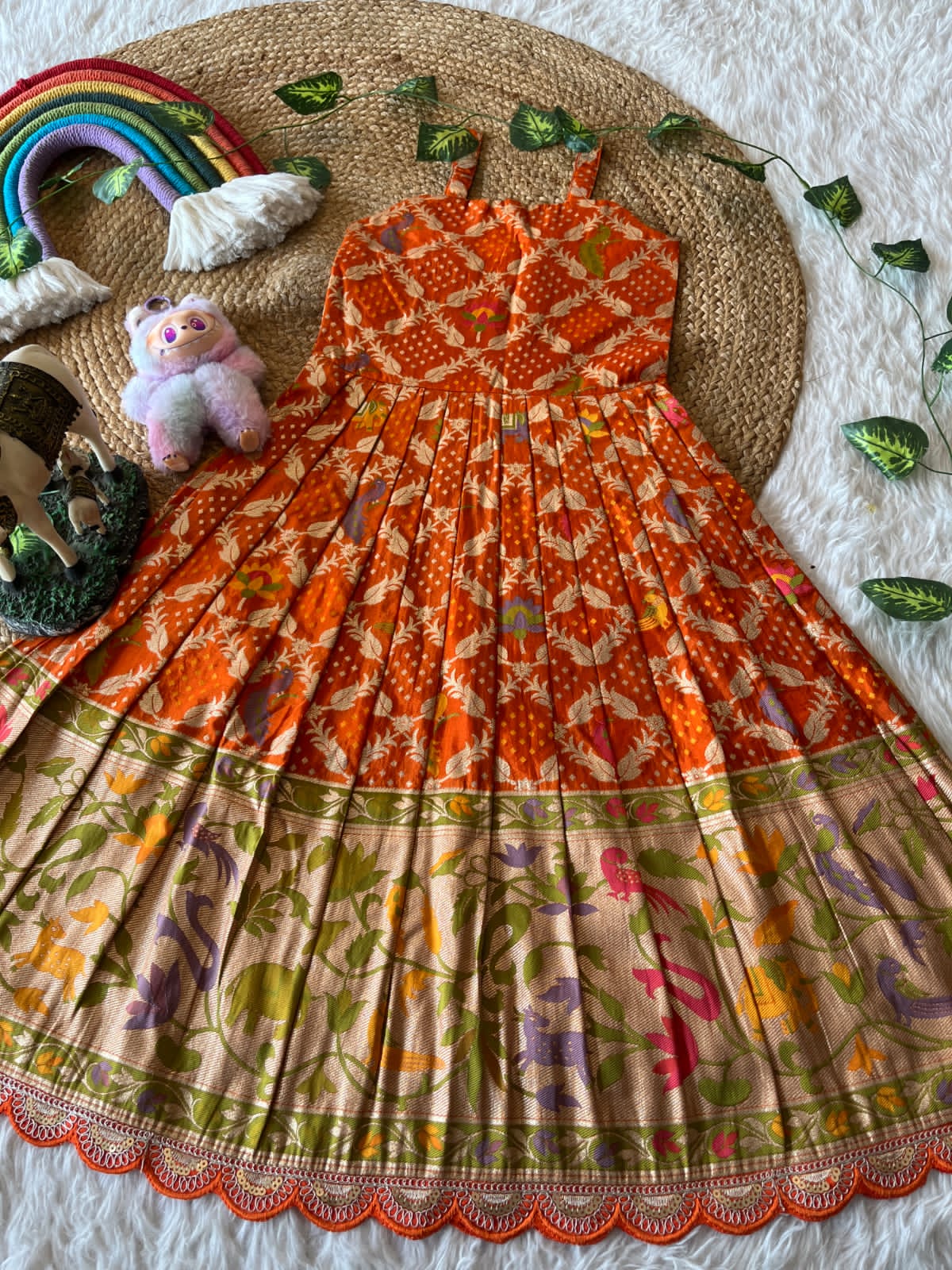 Traditional orange patterned dress on a woven mat with decorative elements