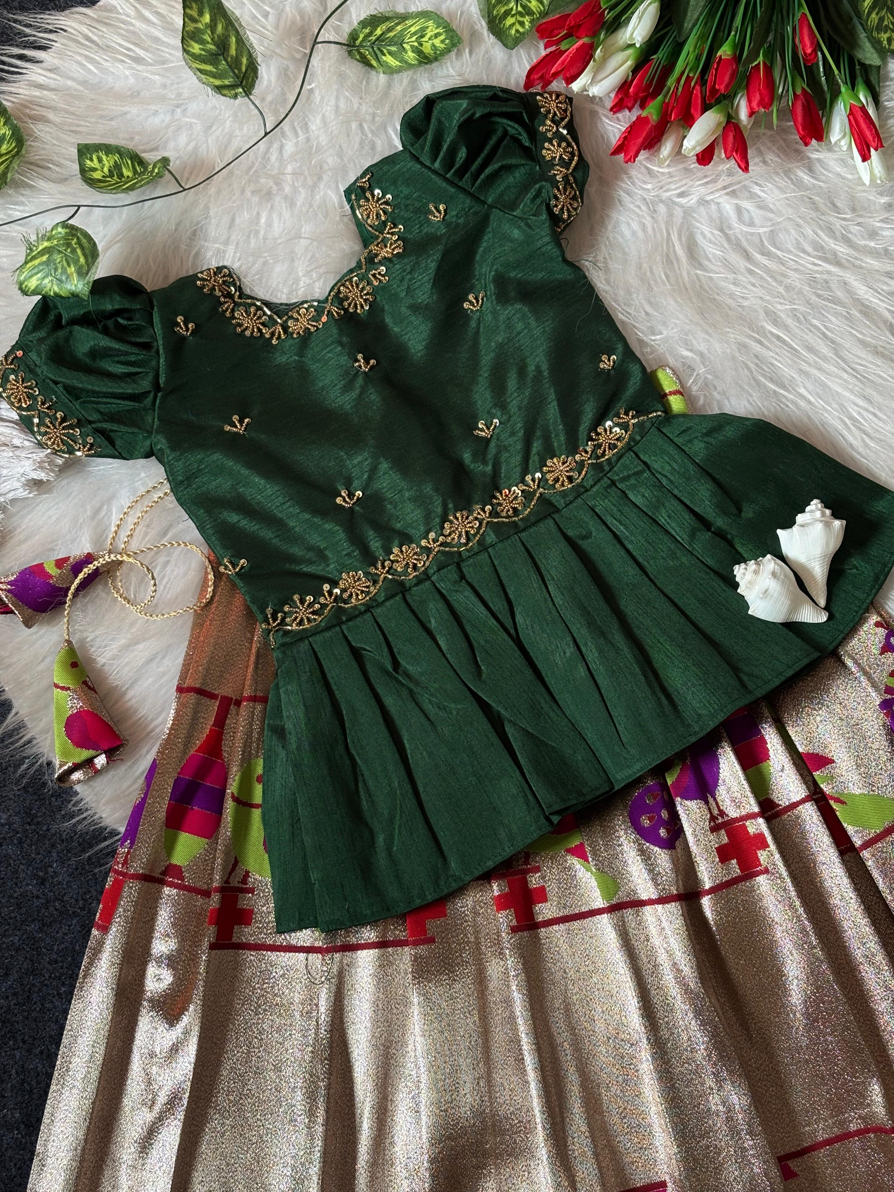 Dark Green dress with gold embroidery on a textured surface with flowers and leaves.