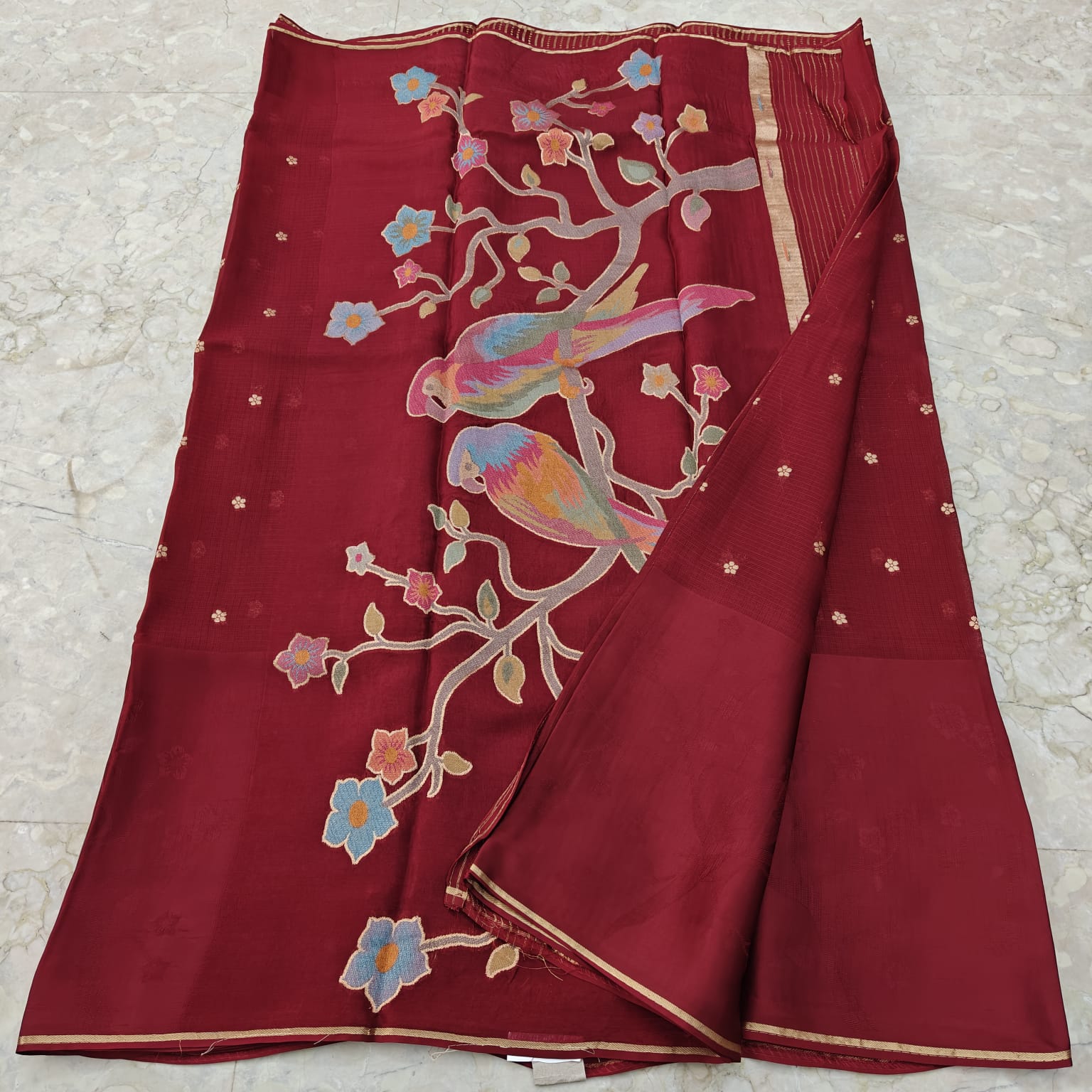 Maroon fabric with colourful birds and floral patterns 