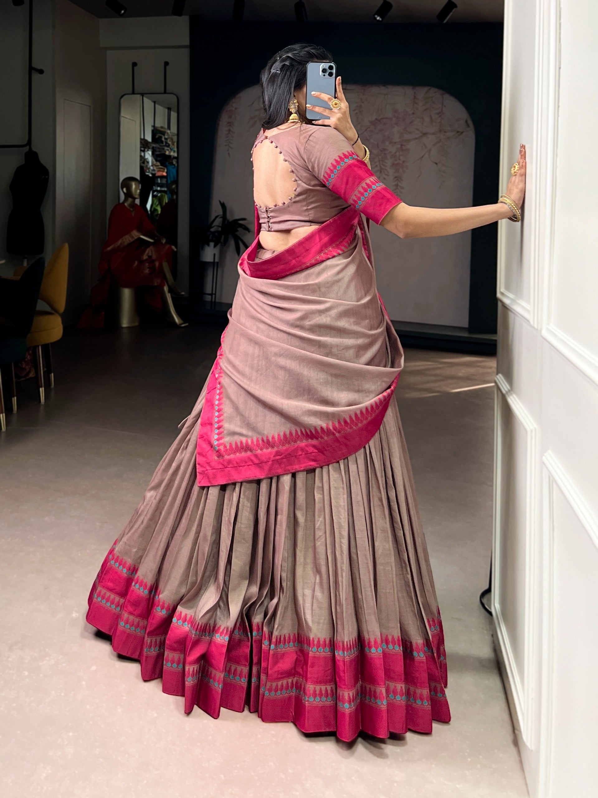 Person wearing a traditional saree with copper colors, standing in a room.