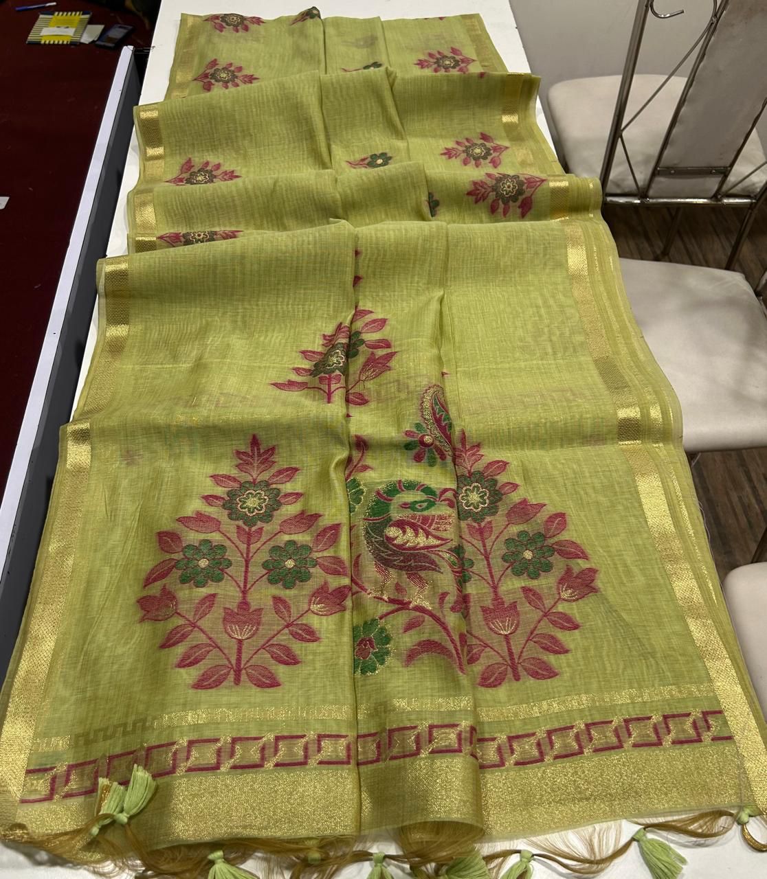 Olive Green embroidered fabric with floral patterns on a white surface