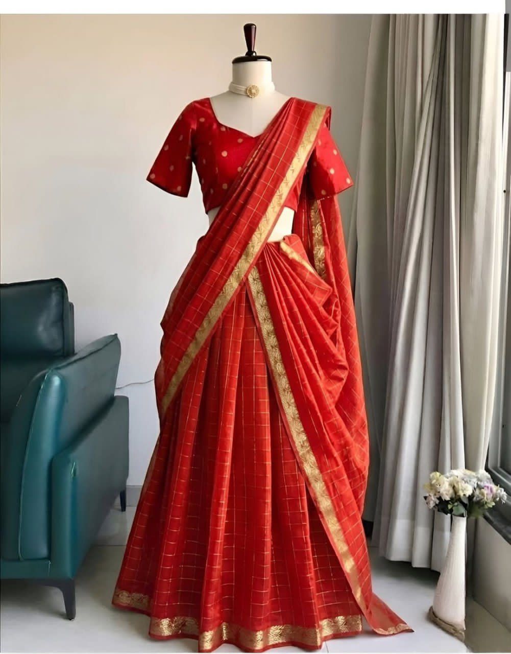 Red saree with gold border on a mannequin against a neutral background