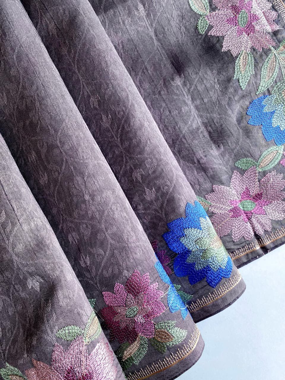 Gray fabric with colorful floral embroidery on a background