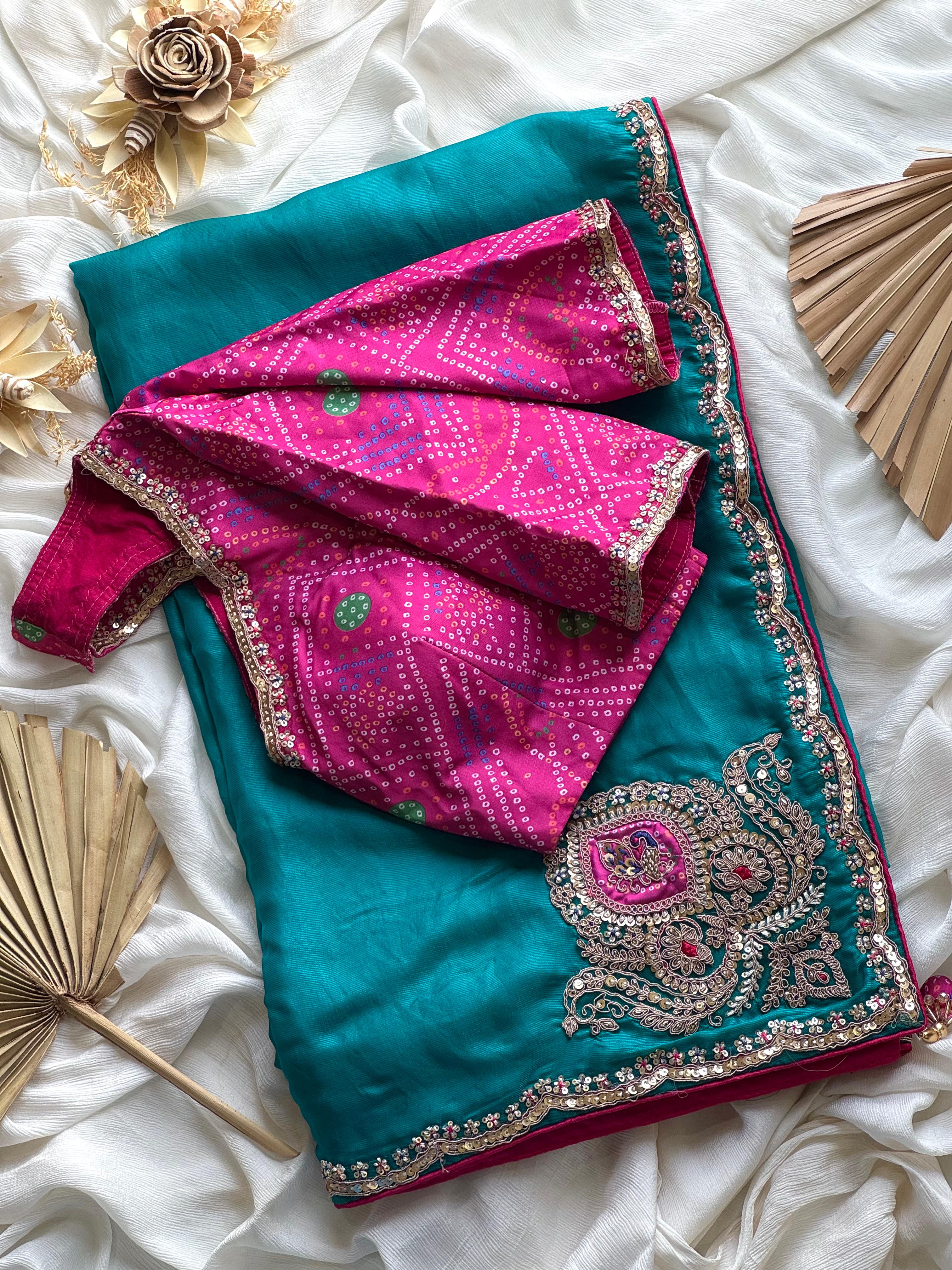 Teal blue and pink saree with intricate patterns on a white fabric background