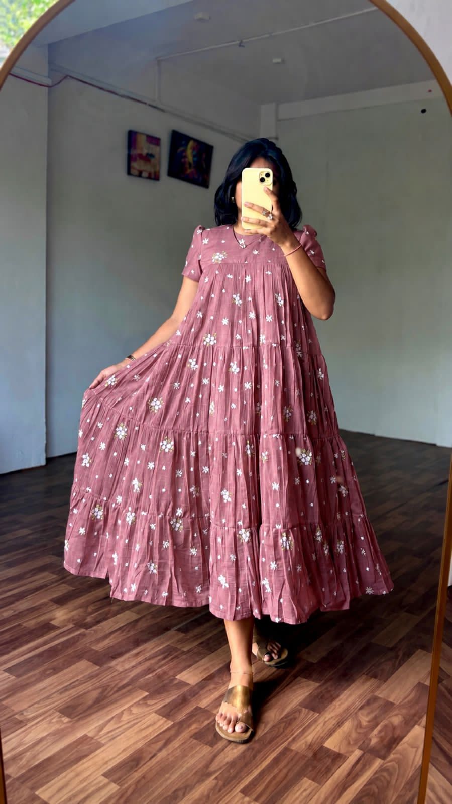Person wearing a onion pink floral dress standing in a room with wooden flooring.