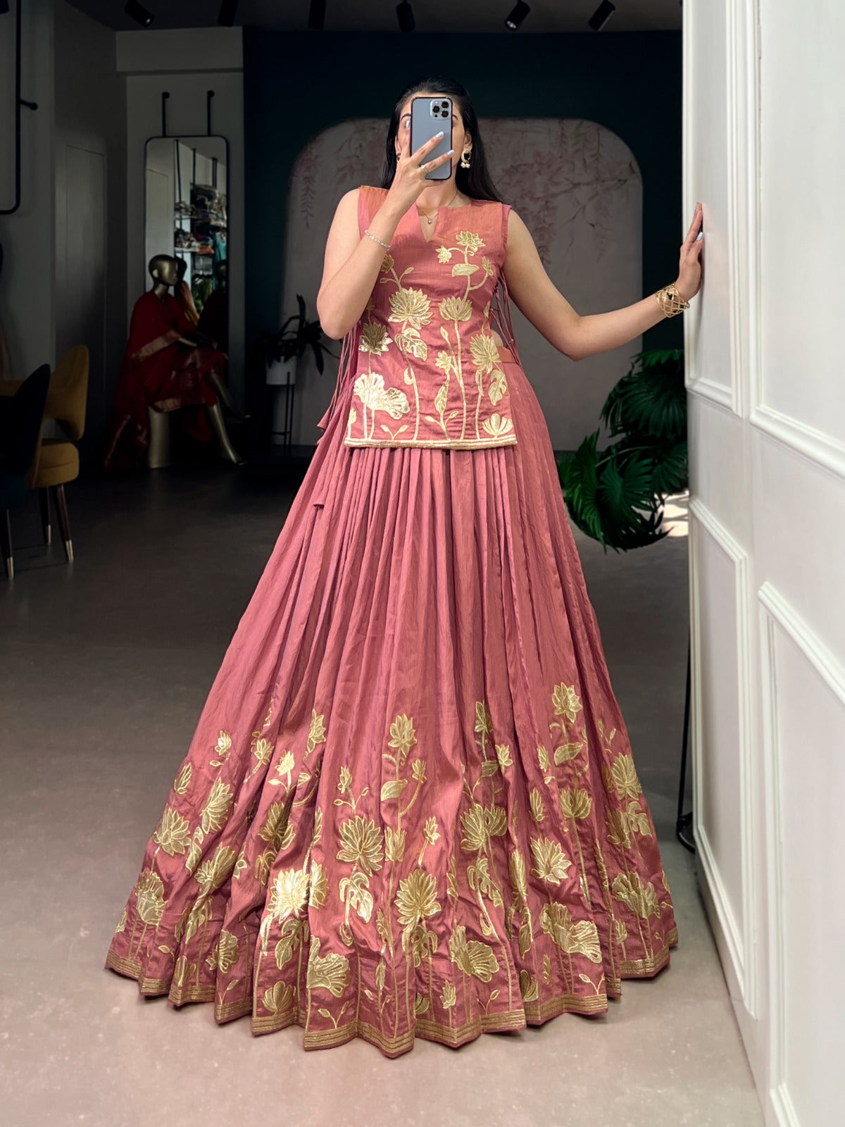 Peach and gold embroidered traditional outfit taking a mirror selfie.