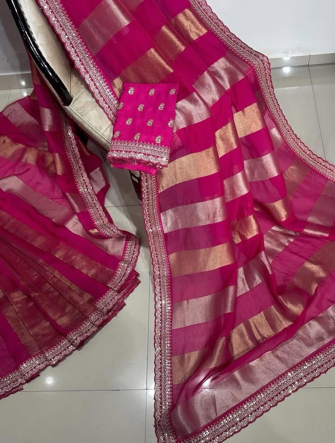 Pink saree with gold stripes on a white floor