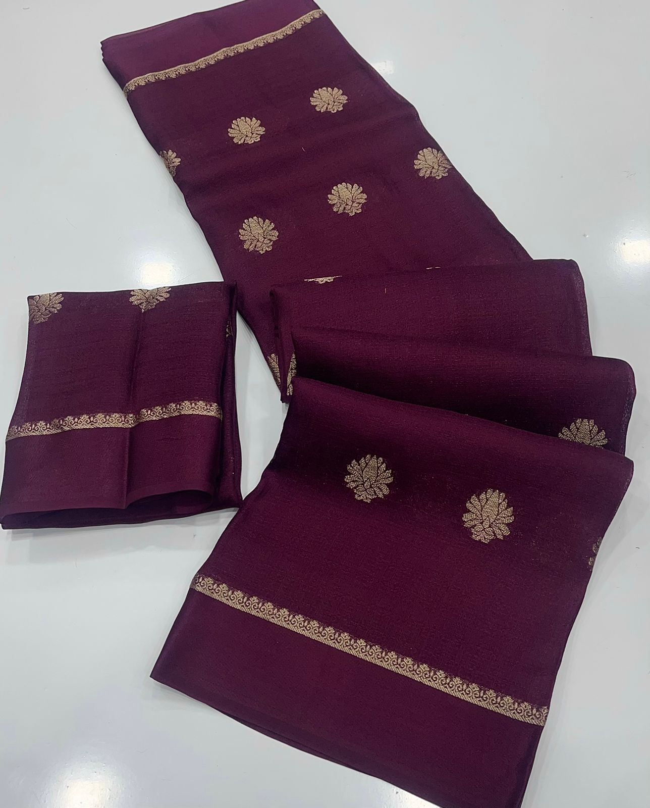 Wine saree with gold embroidery on a white background