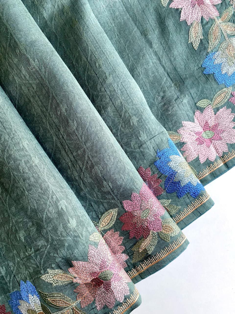 Bottle green fabric with floral patterns on a teal background
