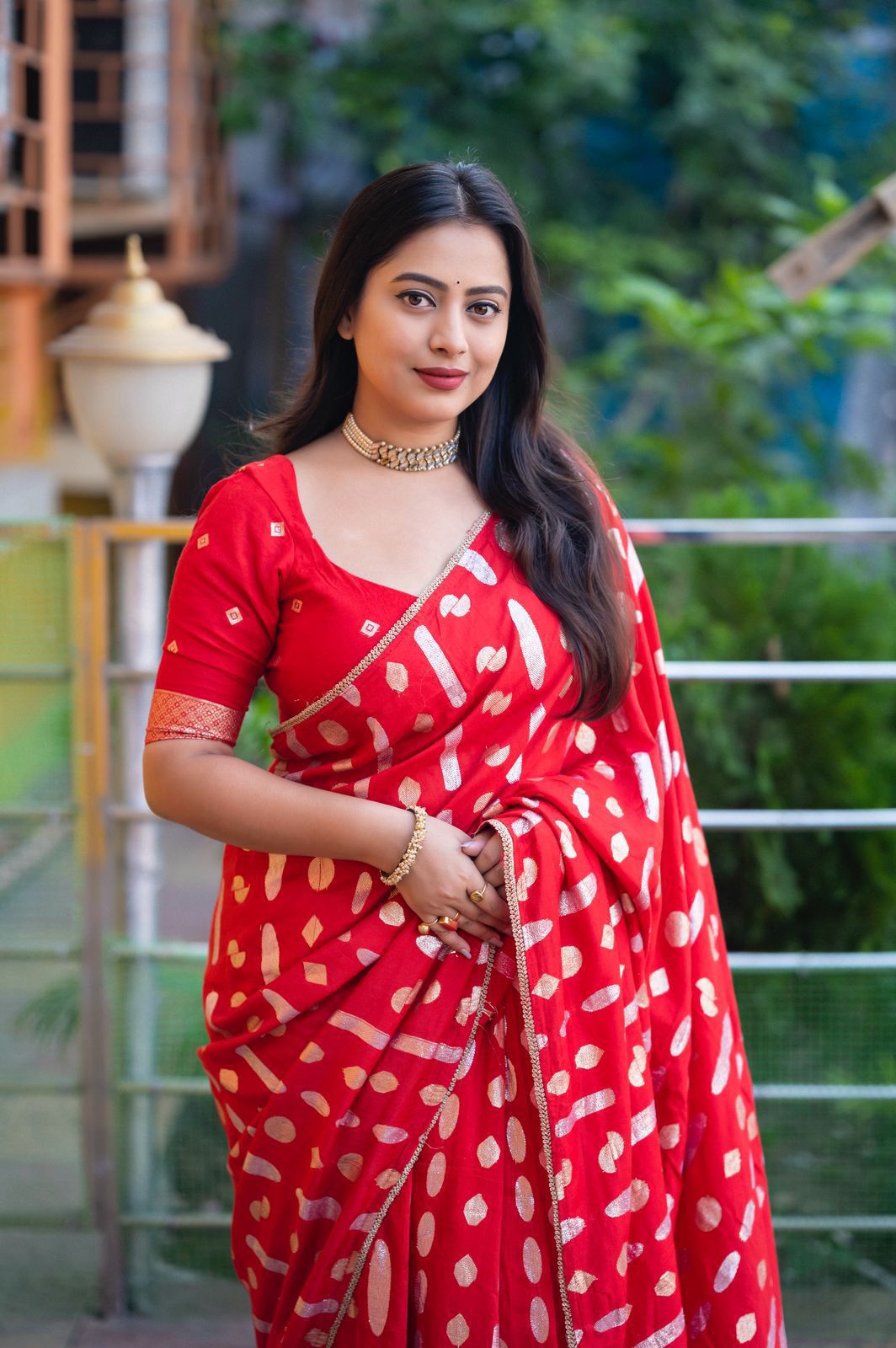 Woman wearing a red saree with white patterns outdoors