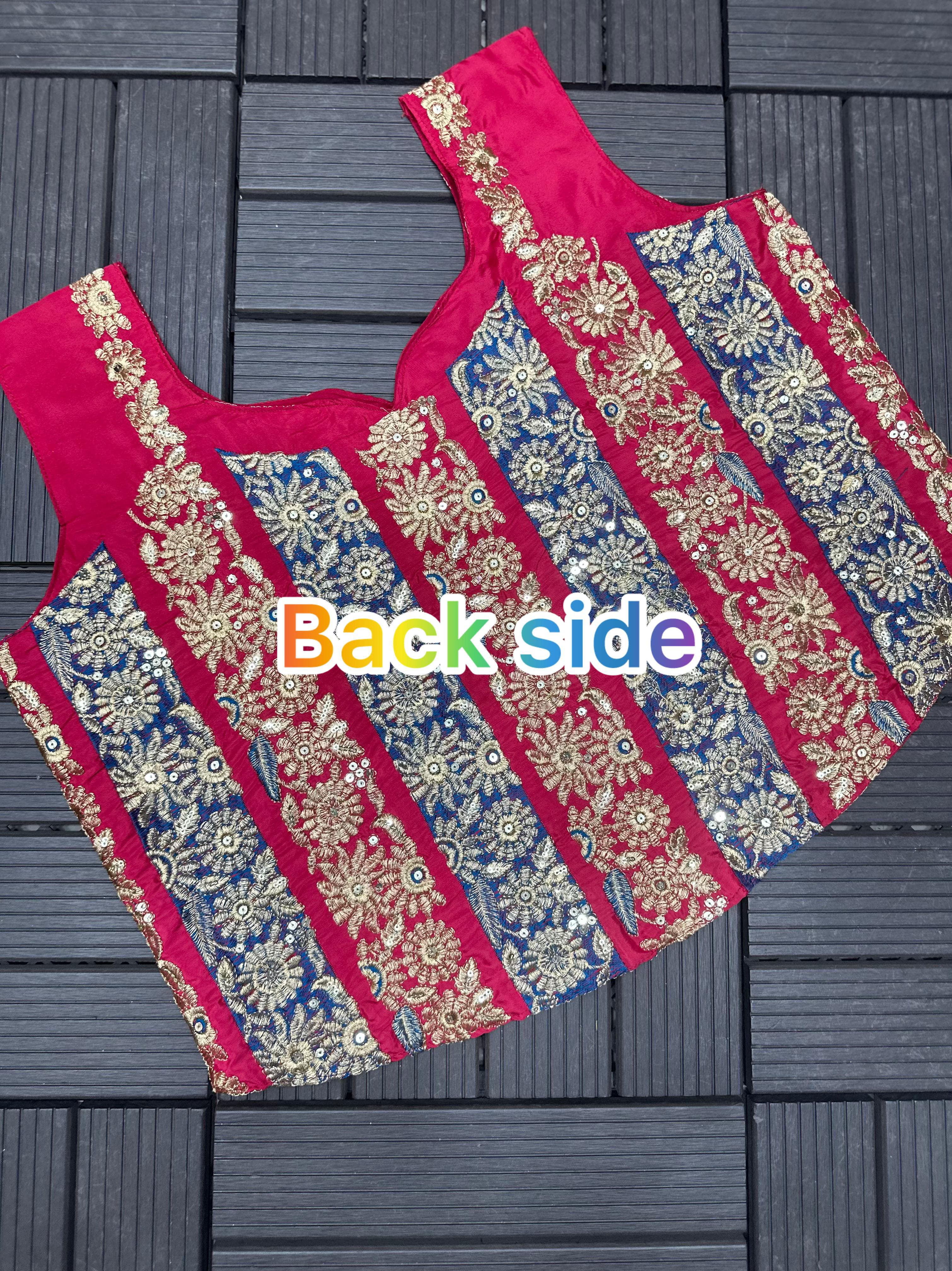 Pink blouse with gold and blue floral patterns on a dark wooden surface