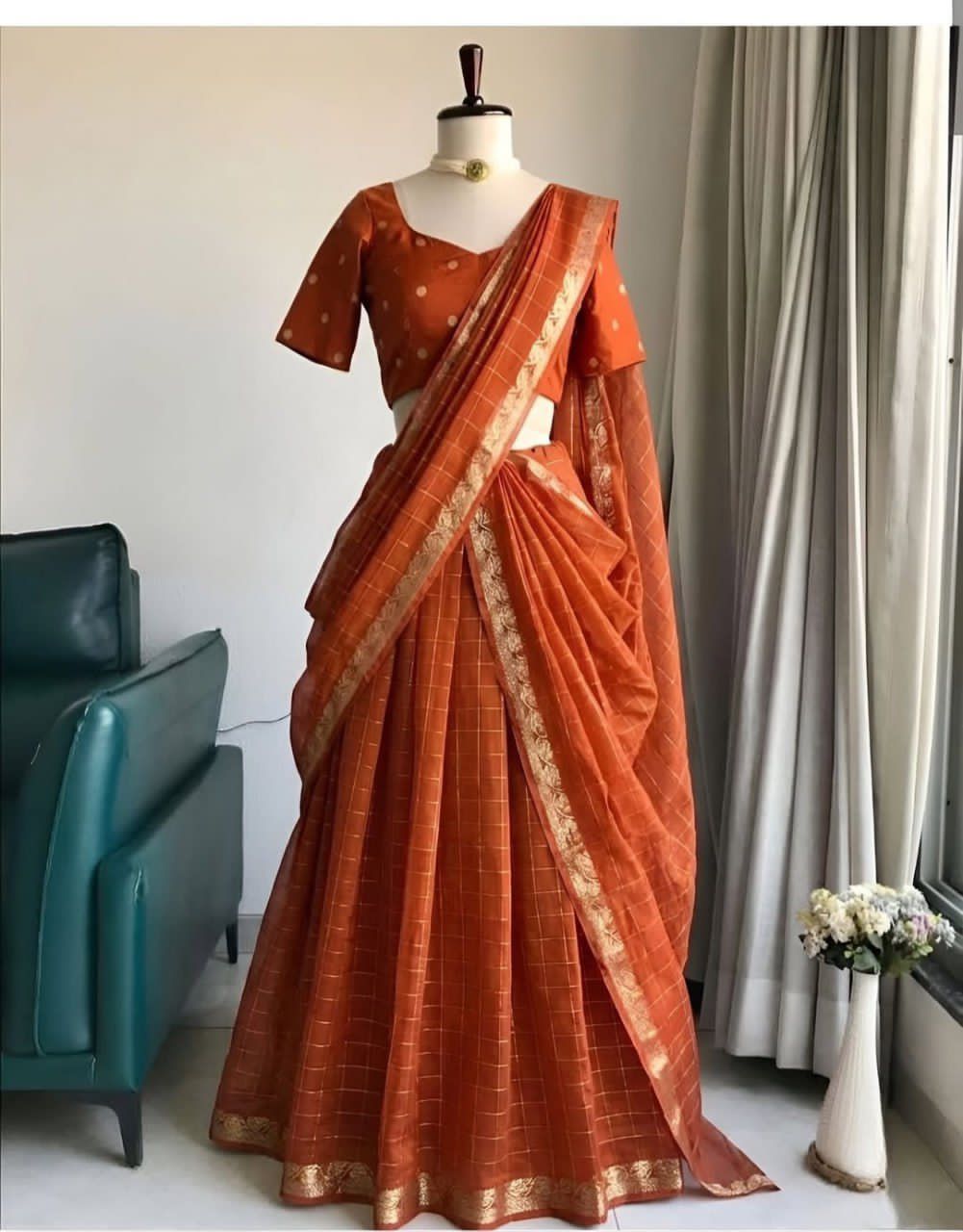Orange saree with gold border on a mannequin against a neutral background
