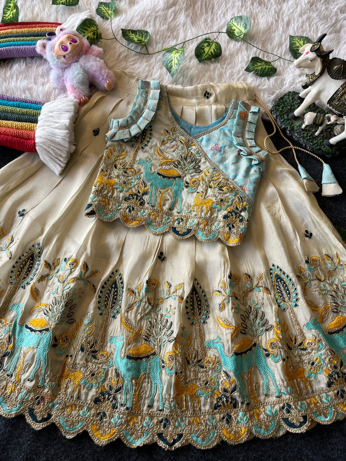 Beige Embroiderey dress with deer pattern on a textured surface with toys and decorations.