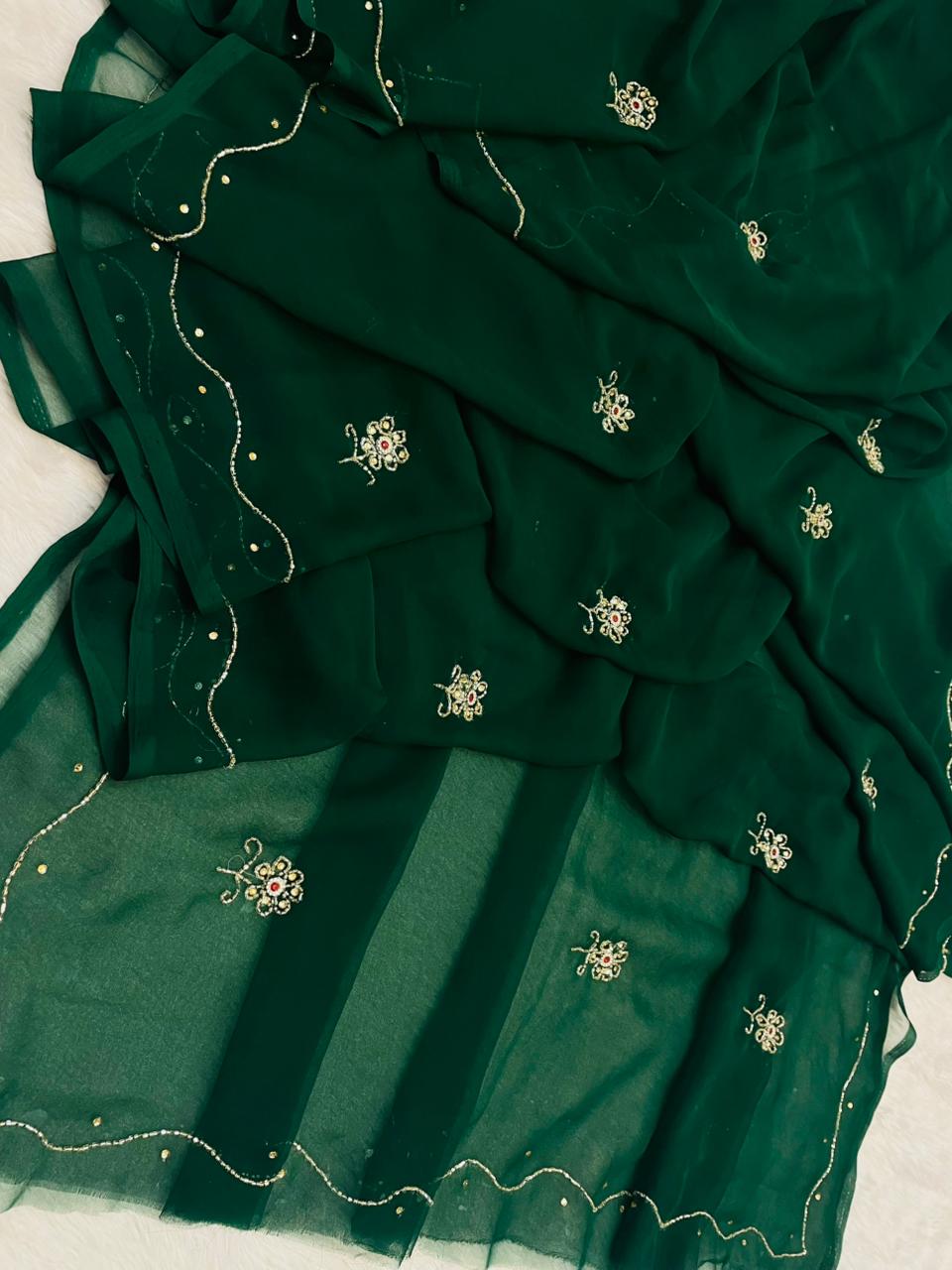 Green fabric with intricate embroidery on a light background
