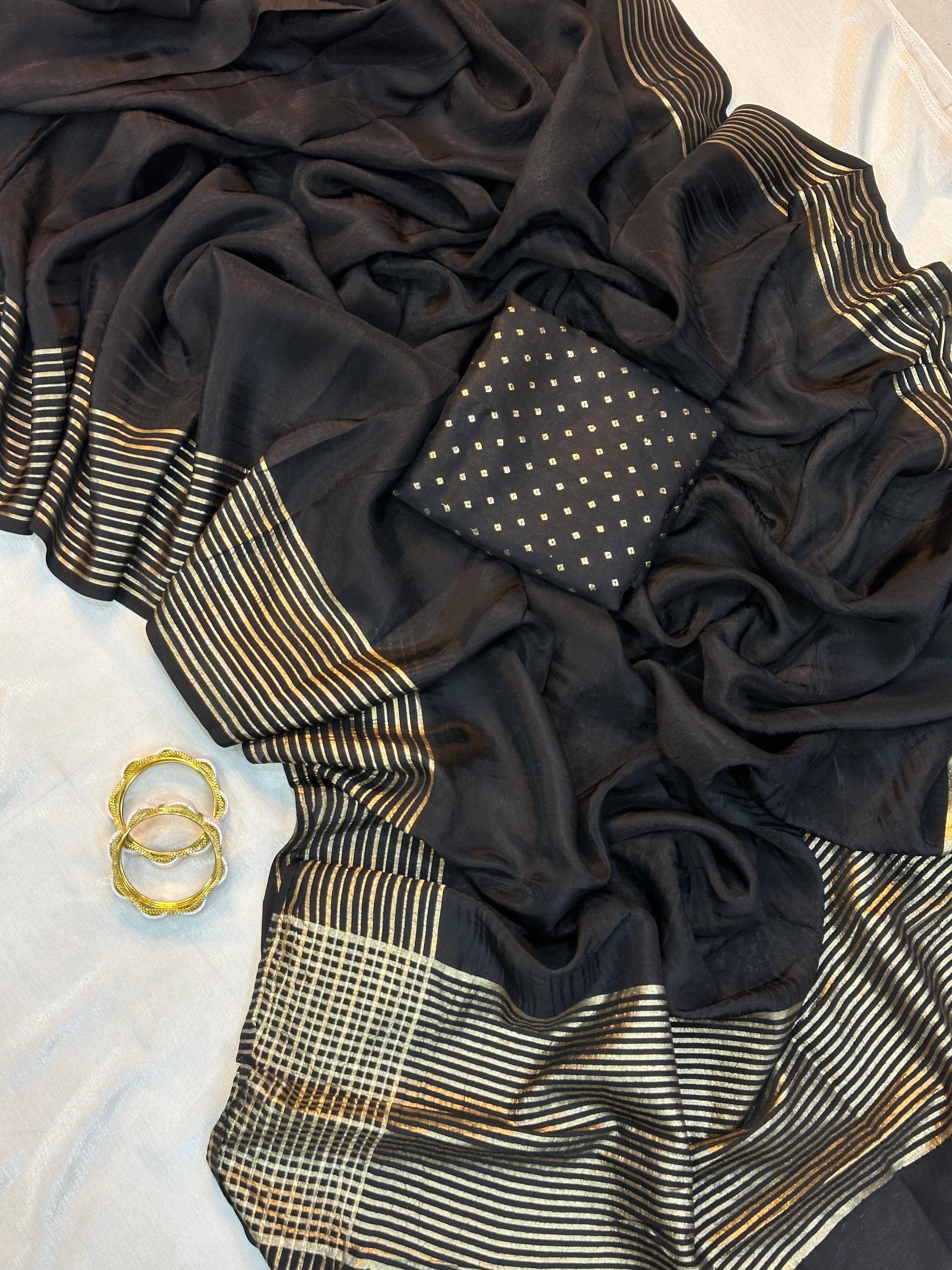 Black fabric with gold patterns and a gold ring on a texture surface