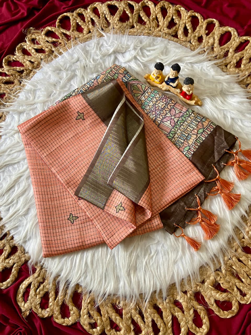 Decorative Peach fabric with intricate patterns and tassels on a texture surface