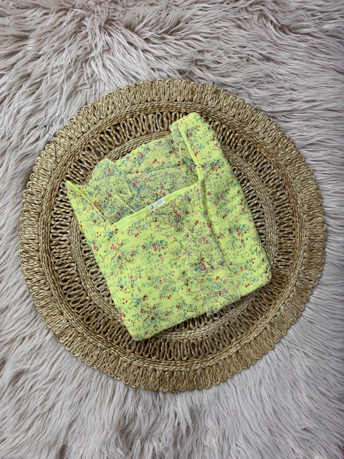Yellow floral fabric on a woven mat with a fluffy gray background