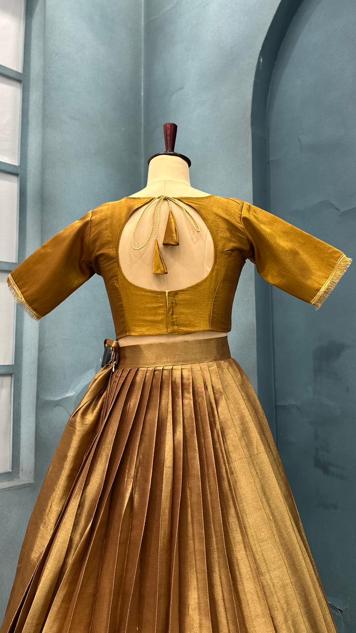 Gold and brown dress on a mannequin against a light blue wall